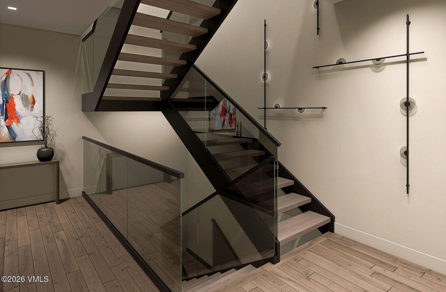 This modern staircase features light wood treads and a striking black metal frame, complemented by clear glass railings that maintain an open, airy feel. The neutral-toned walls are accented by a minimalist black metal wall installation and contemporary artwork, creating a sophisticated and artistic aesthetic. The perspective captures the staircase from a slightly elevated angle, highlighting the clean lines and architectural contrast between the wood, metal, and glass elements.