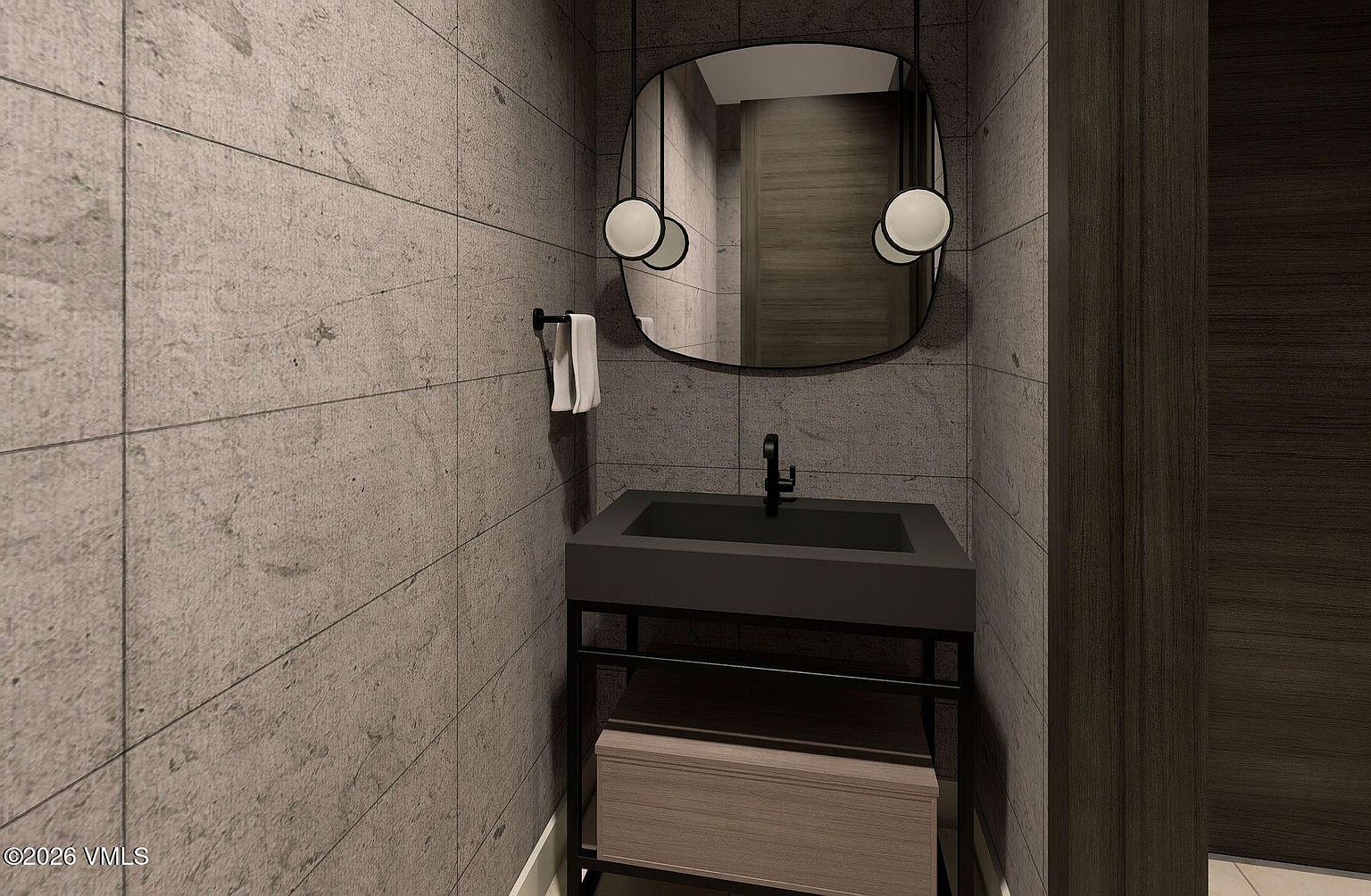 This modern powder room features large-format gray stone wall tiles and a minimalist floating vanity with a dark basin. A unique, rounded rectangular mirror is suspended by two black rods, flanked by spherical pendant lights that provide a contemporary aesthetic. The space is finished with a dark wood door and clean, sharp lines, creating a sophisticated and moody atmosphere.