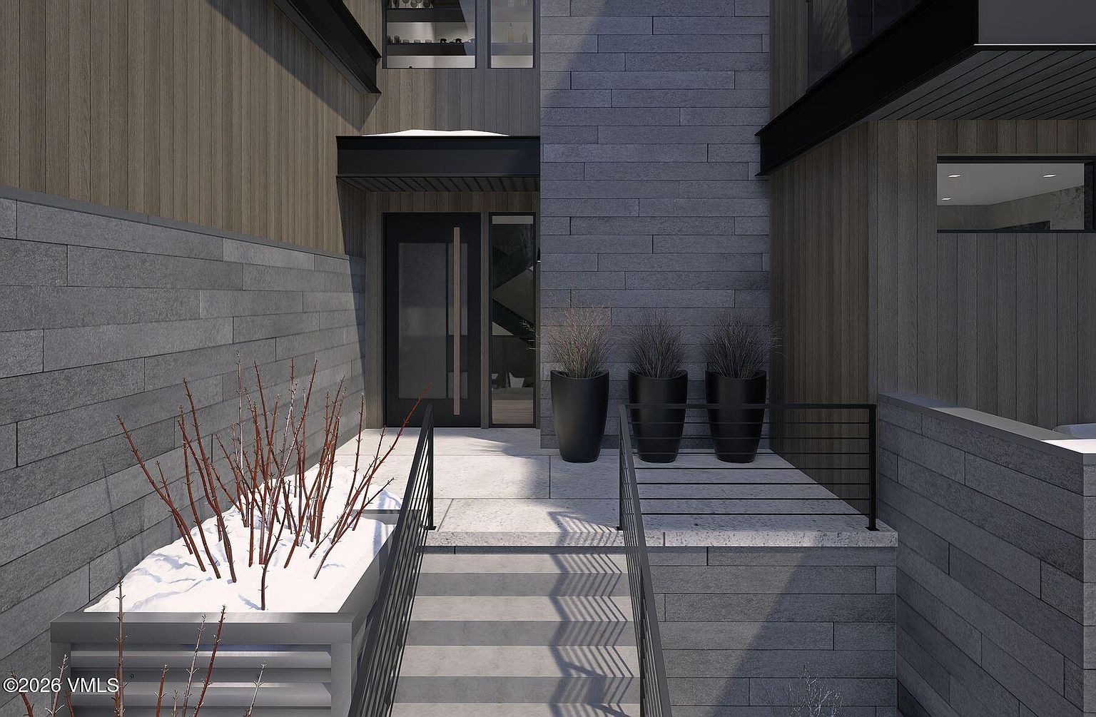 This modern entryway features a striking combination of dark wood siding and textured gray stone cladding, creating a sophisticated and contemporary aesthetic. A set of concrete steps leads up to a glass-paneled front door, flanked by three large, dark planters containing ornamental grasses. The perspective is a low-angle shot looking up toward the entrance, emphasizing the clean lines and architectural depth of the home's facade.