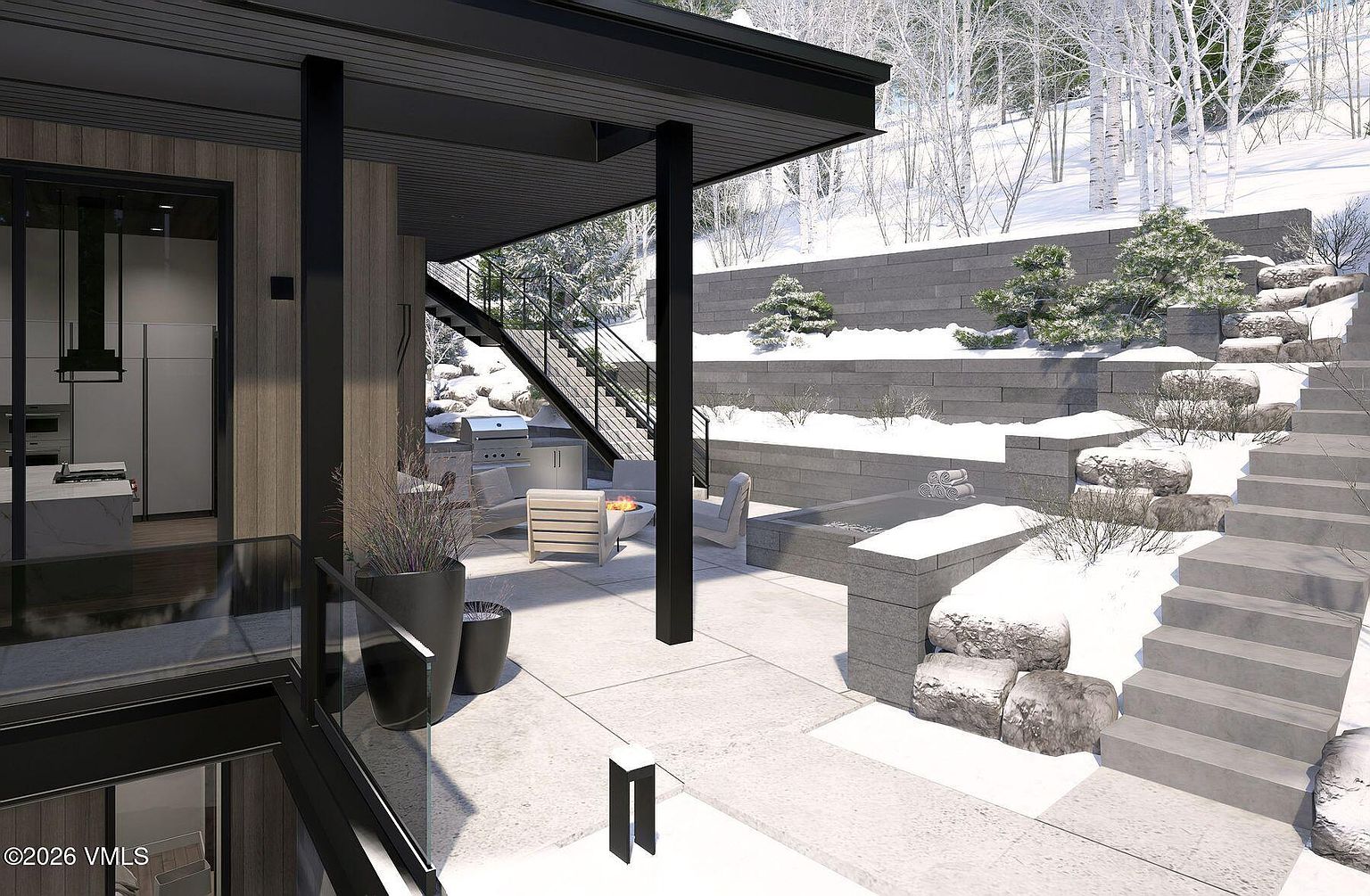 This modern outdoor living space features a covered patio area with a built-in grill and a fire pit surrounded by lounge chairs. A set of concrete stairs leads up a terraced hillside, which is landscaped with stone retaining walls and snow-dusted trees. The design emphasizes a seamless transition between the indoor living area and the exterior, showcasing a contemporary architectural style with clean lines and glass railings.