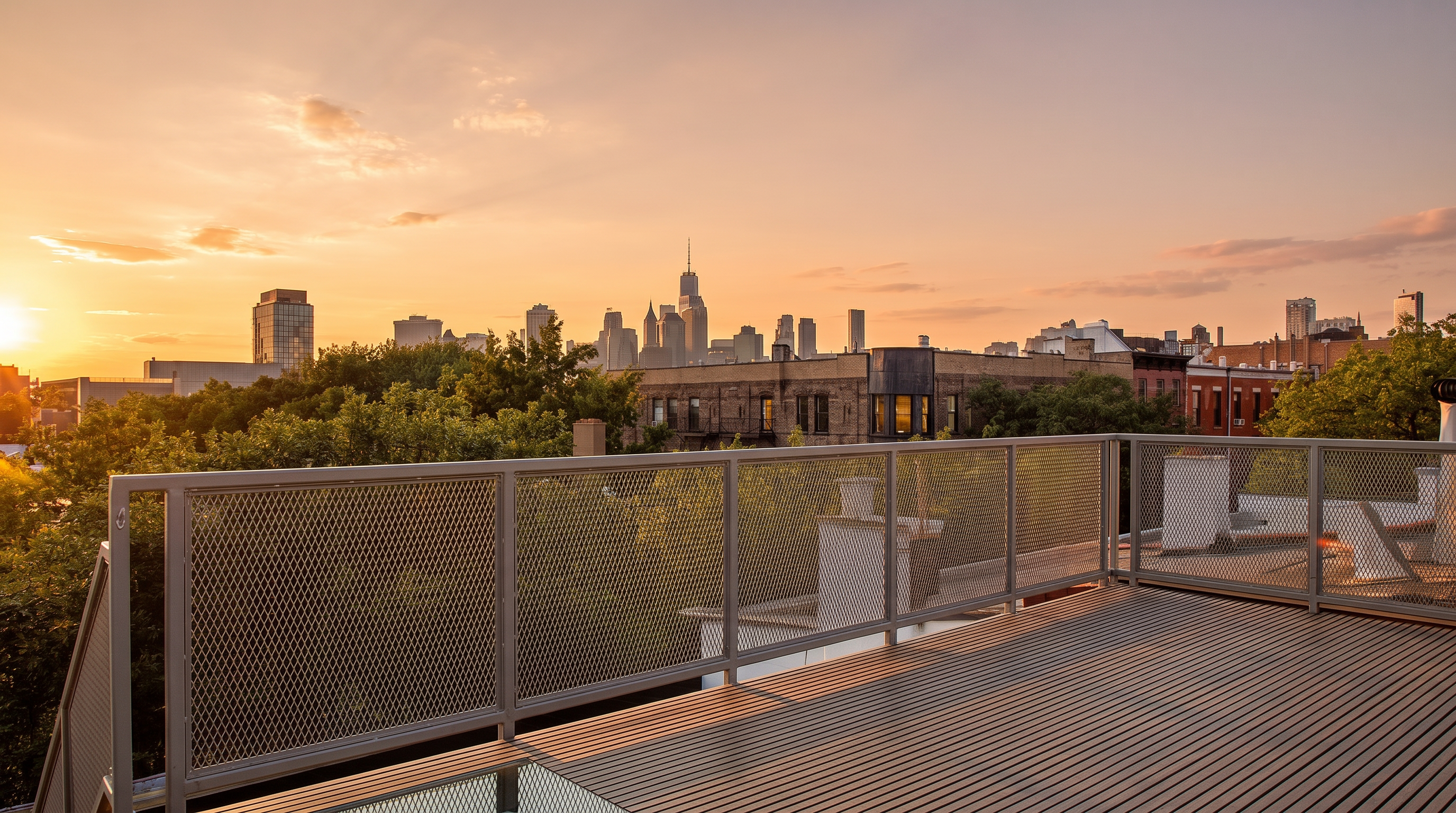 This rooftop deck features modern, slatted wood decking and a sleek metal mesh railing, providing a clean and contemporary outdoor living space. The elevated perspective offers a stunning, unobstructed panoramic view of the city skyline during the golden hour. It is an ideal setting for relaxation or entertaining, capturing the essence of urban luxury living.