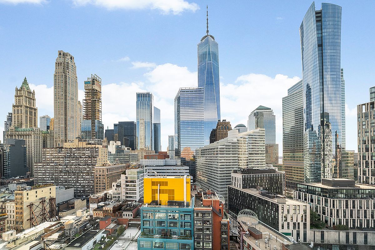 This high-angle aerial view captures a dense, vibrant New York City skyline dominated by the iconic One World Trade Center. The composition showcases a mix of historic masonry buildings and modern glass skyscrapers, highlighting the architectural diversity of the urban landscape. The perspective provides a cinematic sense of scale, emphasizing the bustling metropolitan environment and the proximity to major city landmarks.