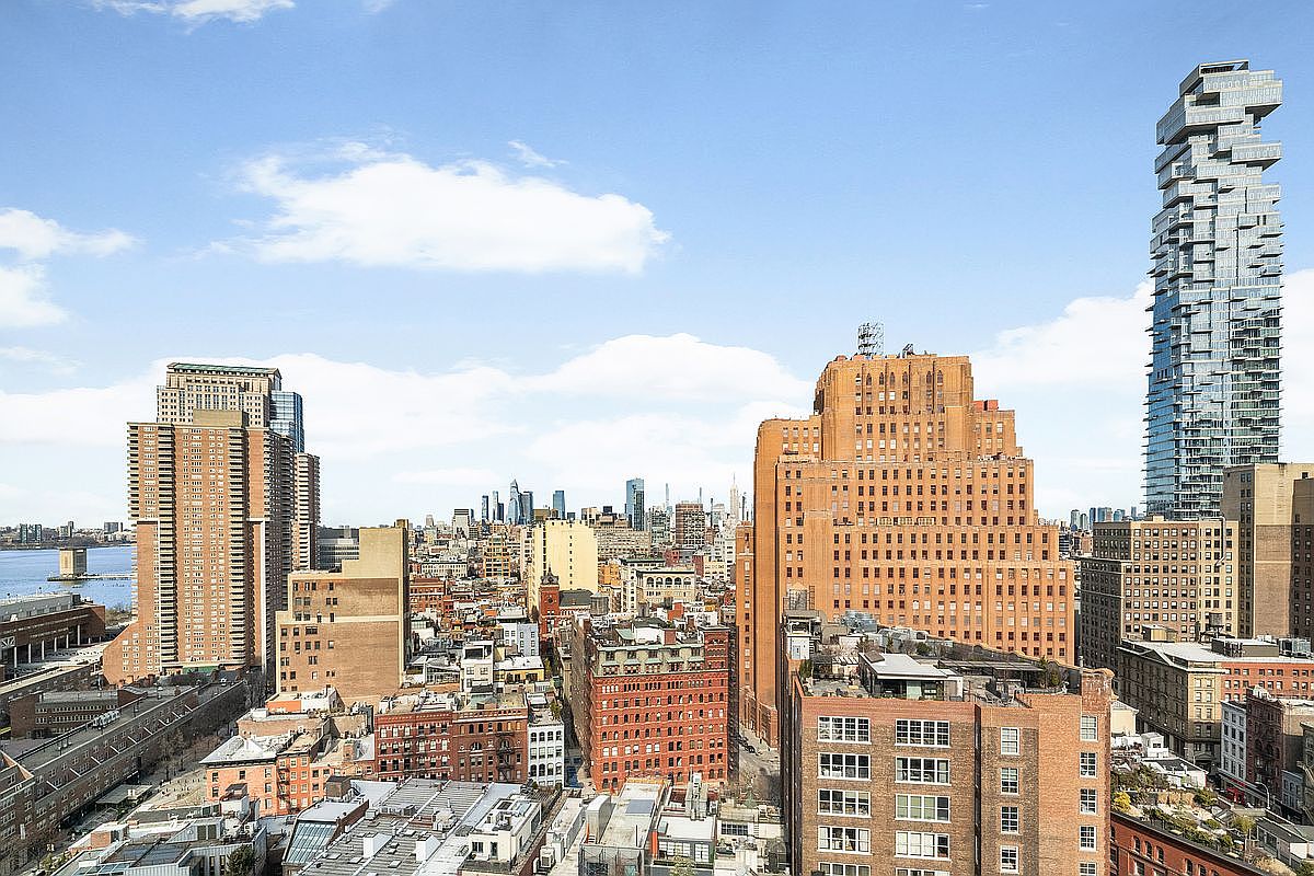 This high-angle aerial view captures a dense urban cityscape, dominated by a mix of historic brick buildings and modern high-rise architecture, including the distinctive Jenga-like structure of 56 Leonard Street. The perspective offers a sweeping look at the city's skyline under a bright, clear blue sky, highlighting the contrast between traditional masonry and contemporary glass design. The scene conveys a sense of vibrant metropolitan life and architectural diversity, ideal for showcasing a prime city location.