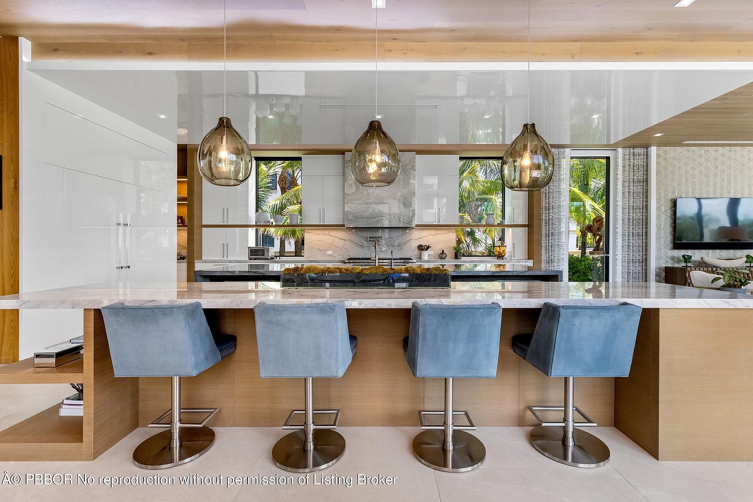 This is a modern kitchen featuring a large island with seating, pendant lighting, and sleek white cabinetry. The kitchen is designed with an open concept, allowing for a seamless transition to other living spaces. The overall impression is one of luxury and sophistication, perfect for entertaining and everyday living.