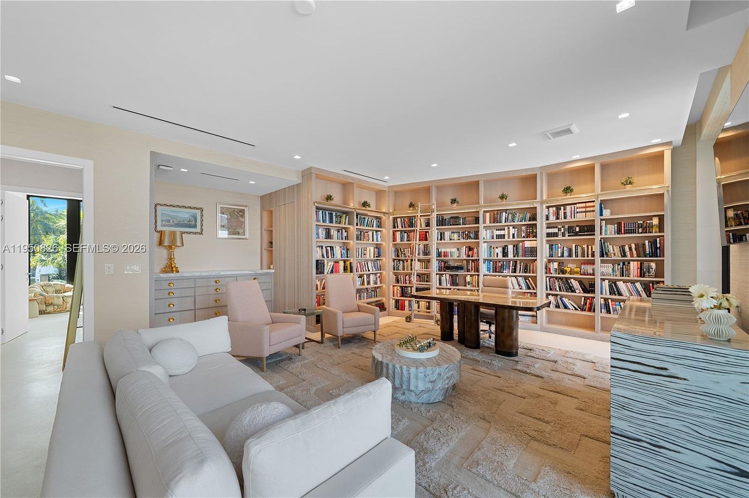 This is an interior shot of a luxurious home office or study, featuring floor-to-ceiling bookshelves filled with books, a large desk, and comfortable seating. The room is well-lit, creating a warm and inviting atmosphere. The style is sophisticated and elegant, perfect for a professional or avid reader.