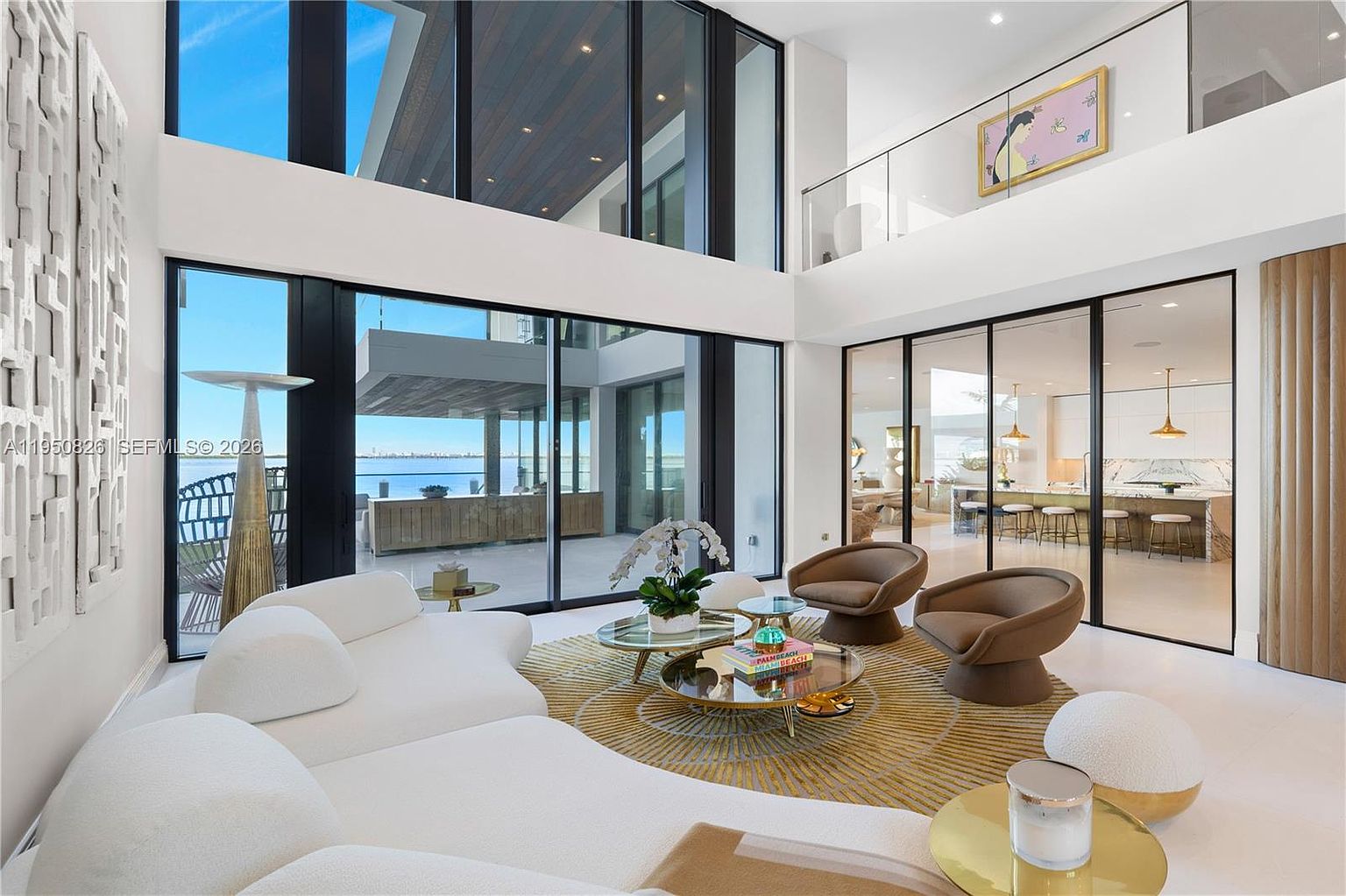 This is a luxurious living room featuring a curved white sofa, modern armchairs, and a unique circular rug. Floor-to-ceiling windows offer stunning views, while the open floor plan seamlessly connects to other areas of the home. The room exudes a sophisticated and contemporary style, perfect for upscale living.