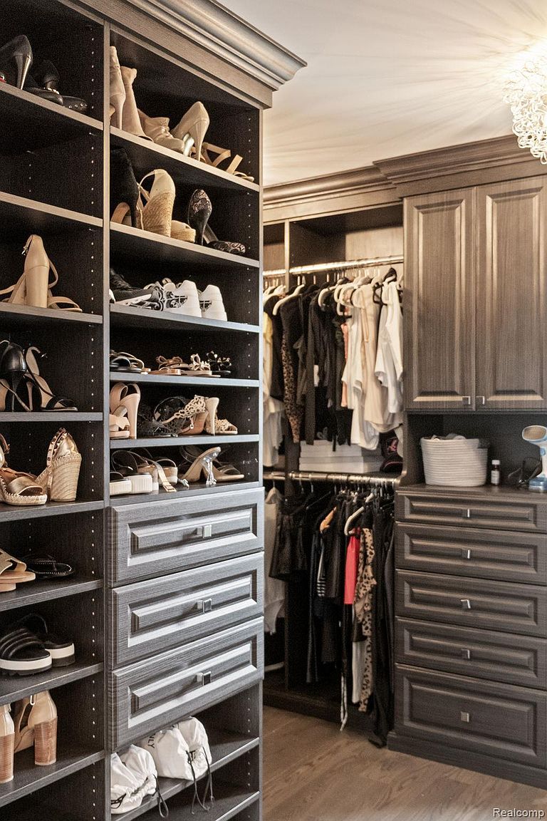 This image showcases a well-organized walk-in closet with custom shelving and drawers. The closet features ample storage space for shoes, clothing, and accessories, all neatly arranged. The dark wood finish and elegant design create a luxurious and functional space, perfect for a real estate listing highlighting upscale amenities.