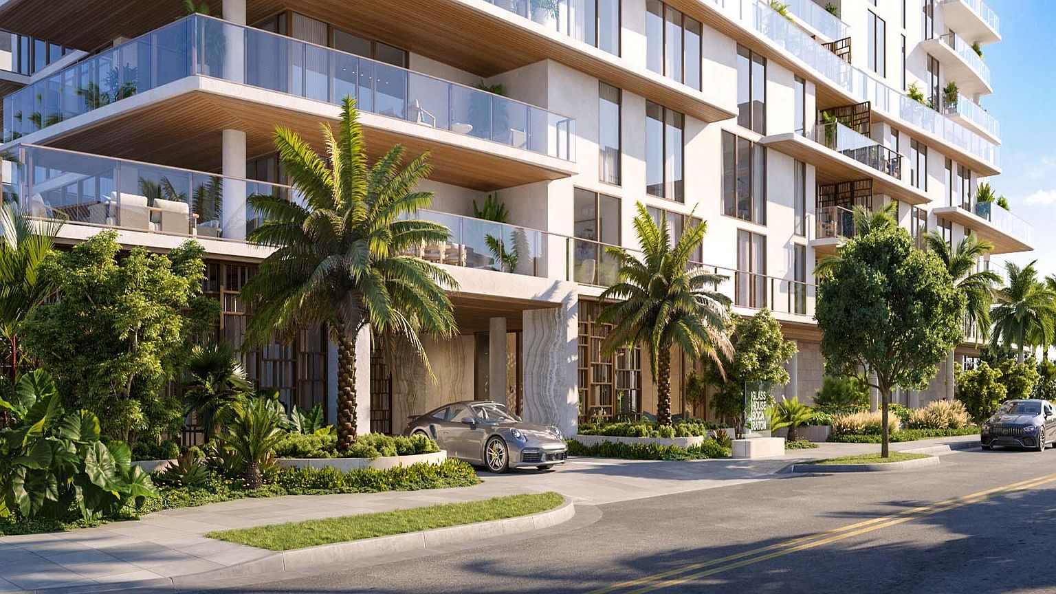This image showcases the front exterior of a modern residential building, featuring multiple balconies with glass railings and a sleek, contemporary design. Palm trees and manicured landscaping enhance the property's curb appeal, while a luxury car parked at the entrance adds a touch of sophistication. The building's facade is predominantly white, creating a bright and inviting atmosphere.