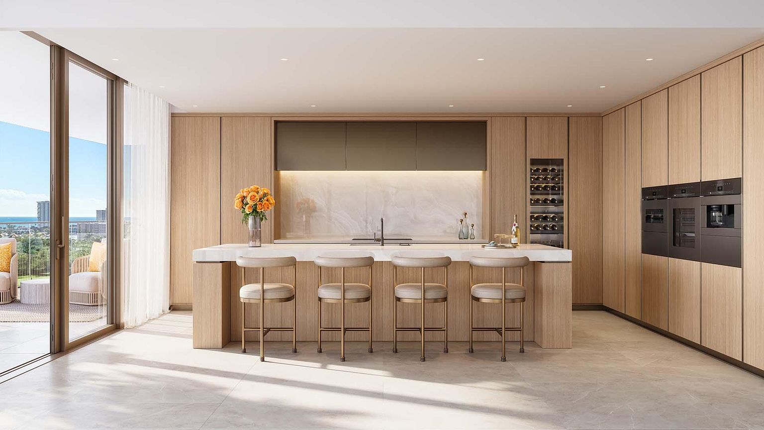 This is a bright and modern kitchen featuring light wood cabinetry, a large island with seating, and high-end appliances. The kitchen has a clean and minimalist design with a marble backsplash and countertops. Large sliding glass doors lead to an outdoor balcony, offering a view of the ocean.