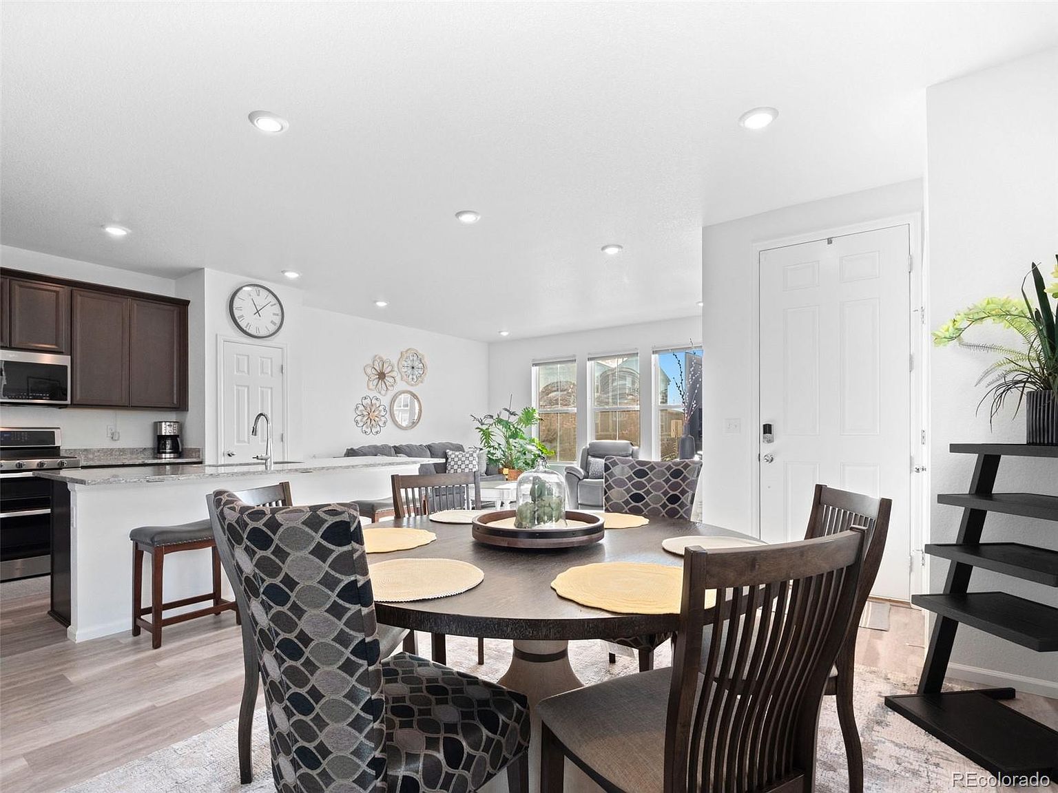 This interior shot showcases a dining room with a round table set for several diners. The room features a modern aesthetic with a neutral color palette, complemented by stylish chairs and a decorative centerpiece on the table. The space is well-lit, creating a welcoming and comfortable atmosphere for dining and entertaining.