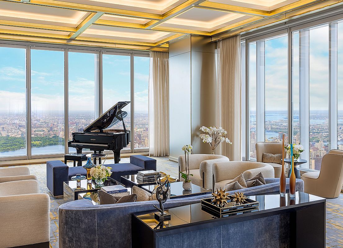 This luxurious, high-rise living room features floor-to-ceiling windows that offer a breathtaking panoramic view of the city skyline and a nearby park. The space is elegantly furnished with a grand piano, plush velvet sofas, and sophisticated modern decor, all set beneath a stunning coffered ceiling with integrated lighting. The overall aesthetic is one of refined opulence and contemporary elegance, perfectly suited for high-end urban living.