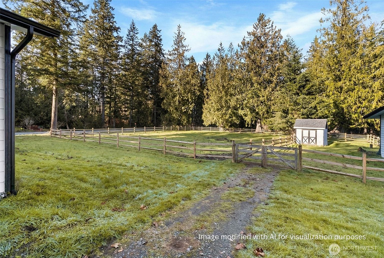 This exterior shot showcases a spacious yard with a wooden fence enclosing a grassy field, bordered by tall trees. A dirt path leads through a gate, adding a rustic charm. A small shed is visible in the background, suggesting potential for storage or a hobby space.