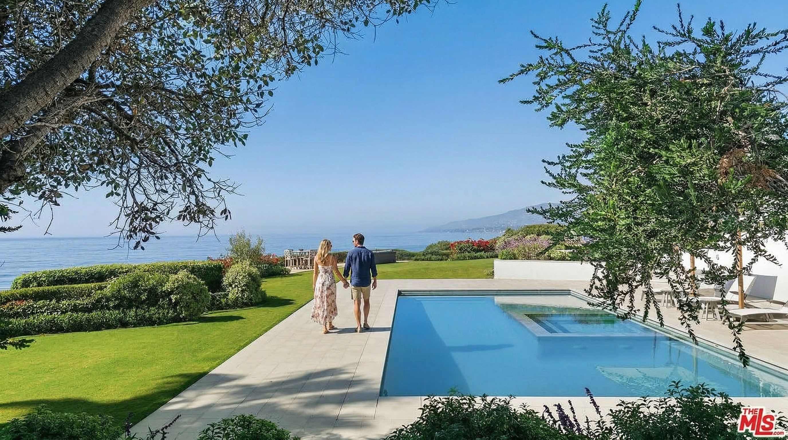 This stunning outdoor space features a sleek, rectangular infinity-edge pool with an integrated spa, perfectly positioned to overlook the vast ocean horizon. The manicured lawn and lush landscaping frame the scene, while a patio area with outdoor seating provides a serene spot for relaxation. The perspective captures the seamless blend of luxury architecture with the natural beauty of the coastal landscape.