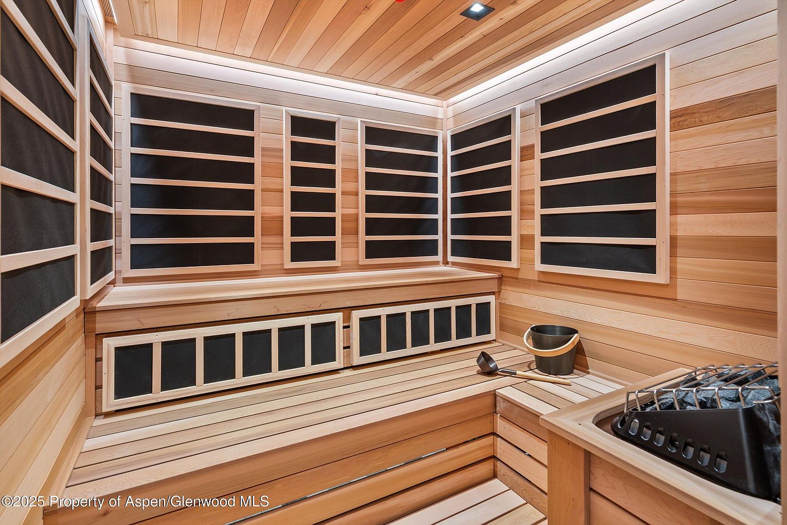 This is an interior shot of a sauna, featuring wooden walls, benches, and a heater. The sauna is well-lit with integrated lighting, creating a warm and inviting atmosphere. The overall impression is one of relaxation and wellness, highlighting a desirable amenity for a potential buyer.