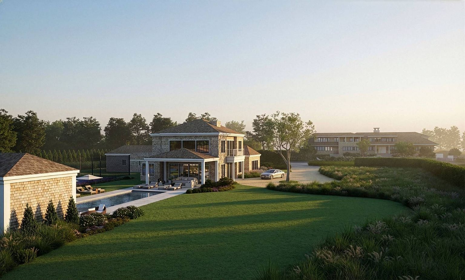 This cinematic wide shot captures the rear exterior of a sprawling, multi-structure estate at dusk. The primary residence features stone cladding, a multi-pitched roof, and a covered patio overlooking a rectangular swimming pool with lounge seating. A manicured lawn stretches across the foreground, while a secondary building is visible in the distance, connected by a gravel driveway where a luxury sedan is parked.