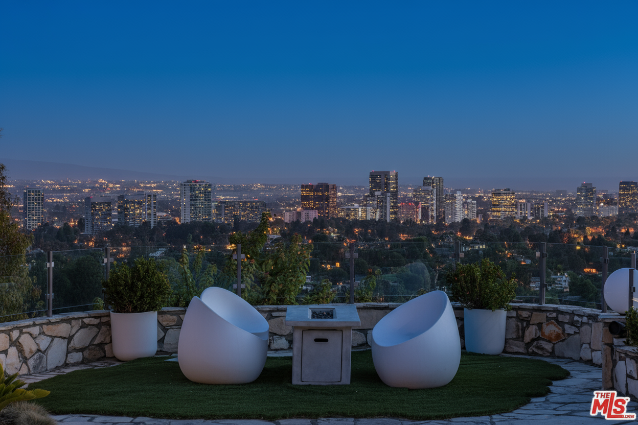 This image showcases a stylish outdoor patio or balcony at dusk. The space is furnished with modern white egg-shaped chairs and a fire pit, providing a comfortable and elegant seating area. In the background, a stunning city skyline adds a touch of luxury and emphasizes the property's desirable elevated location and panoramic views.