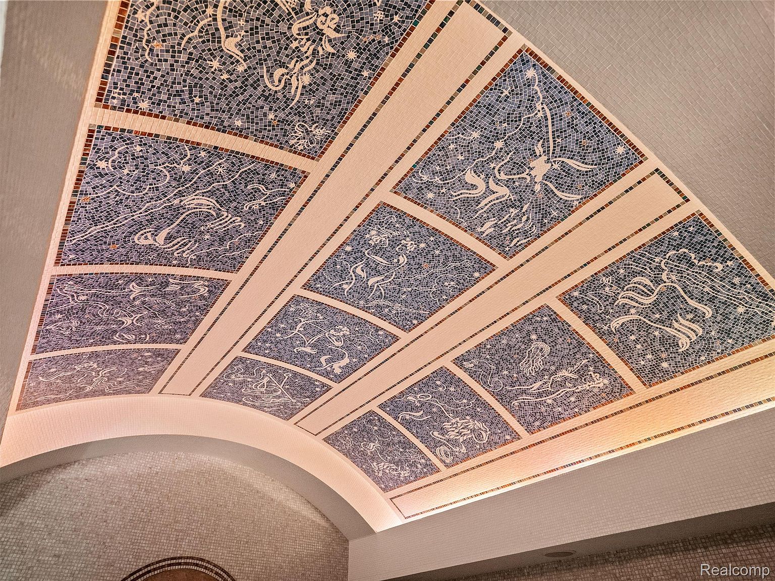 The image showcases a beautifully designed ceiling with mosaic artwork, featuring intricate patterns and celestial-themed illustrations. The ceiling is divided into sections by light-colored beams, creating a visually appealing and unique architectural element. The overall impression is one of artistic elegance and sophisticated design, adding a touch of luxury to the space.
