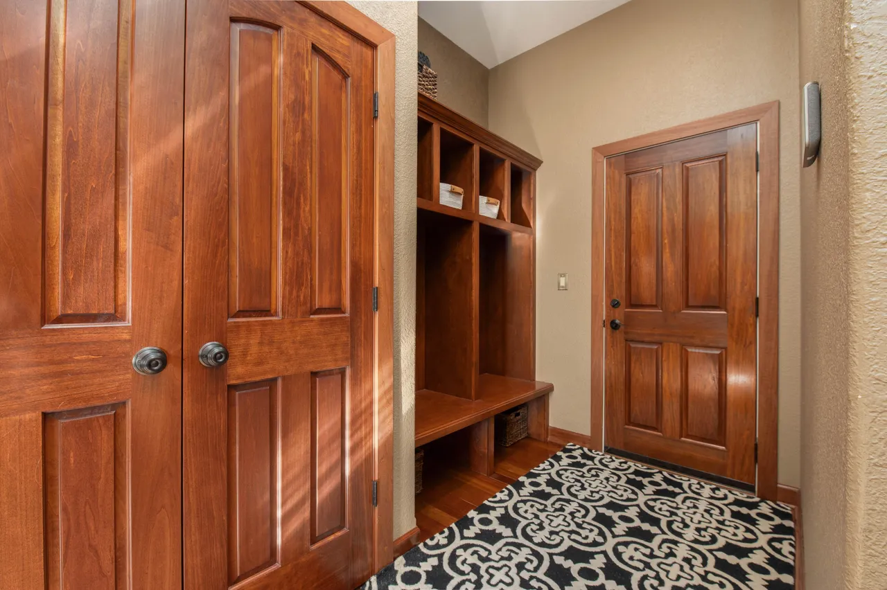 This interior shot showcases a well-maintained entryway or hallway. The space features rich, wooden doors and a built-in storage unit/mudroom area. A patterned rug adds visual interest to the space, suggesting a warm and inviting atmosphere.