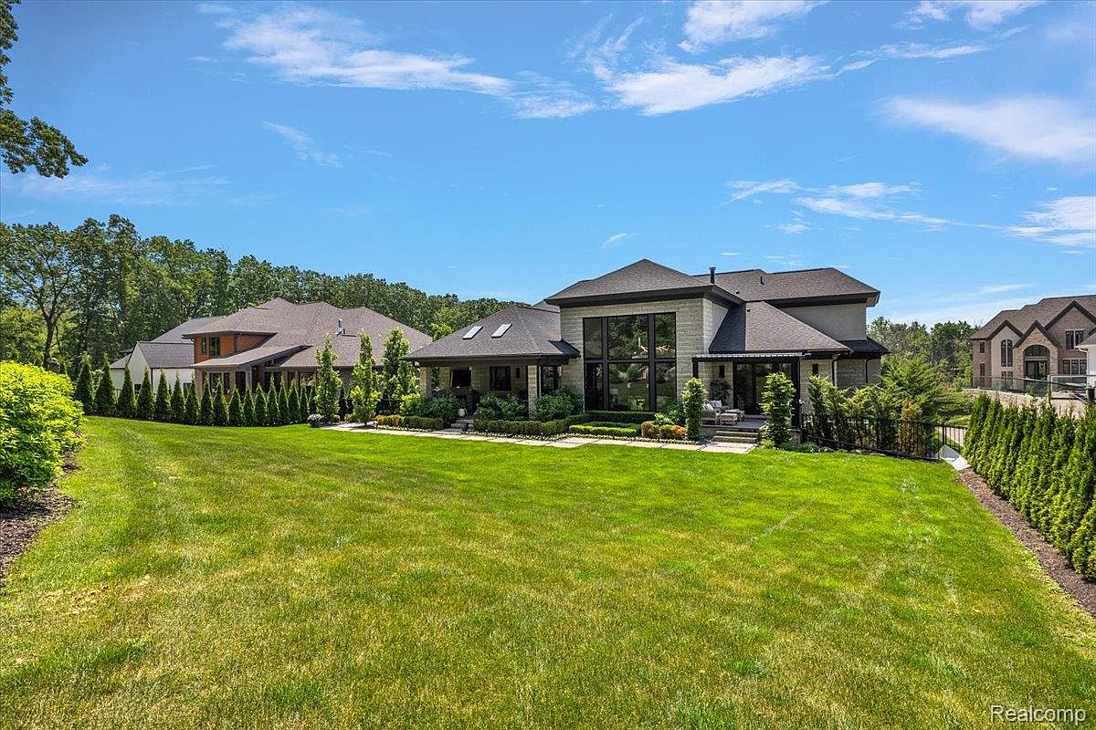This image showcases a sprawling, well-manicured lawn leading up to a luxurious modern home. The property features mature trees and landscaping, enhancing its curb appeal. The overall impression is one of spaciousness and tranquility, ideal for outdoor living and entertaining.