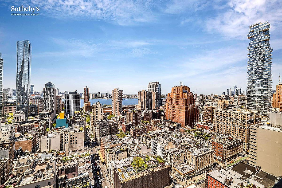 This aerial view showcases a dense urban landscape with numerous skyscrapers and buildings under a partly cloudy sky. The architectural styles vary, with some buildings featuring modern glass facades and others displaying classic brickwork. The image provides a sense of the city's scale and vibrancy, highlighting its diverse architectural character.