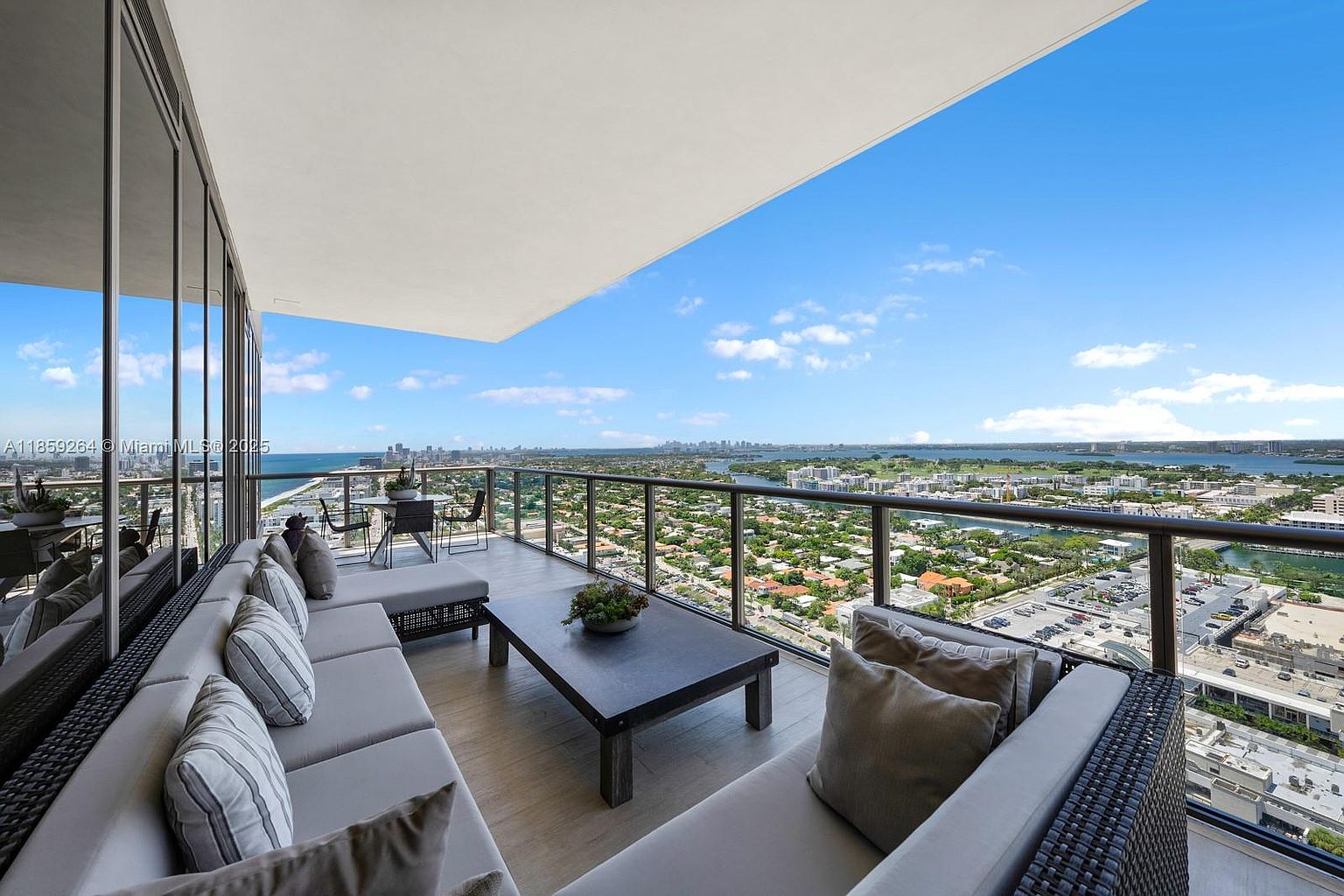 This image showcases a luxurious balcony with comfortable outdoor seating, including a sectional sofa and a coffee table. The balcony offers stunning panoramic views of the city skyline, ocean, and surrounding landscape. The space is designed for relaxation and entertainment, making it an appealing feature for potential buyers.