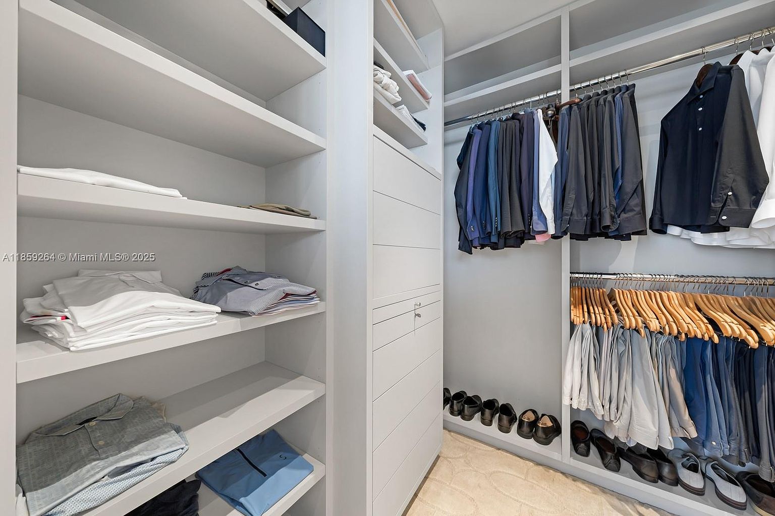 This image showcases a well-organized walk-in closet with custom shelving and hanging rods. The closet features a variety of clothing items, including suits, shirts, and pants, neatly arranged. The neutral color palette and ample storage space create a functional and aesthetically pleasing environment, ideal for showcasing the home's organizational features.