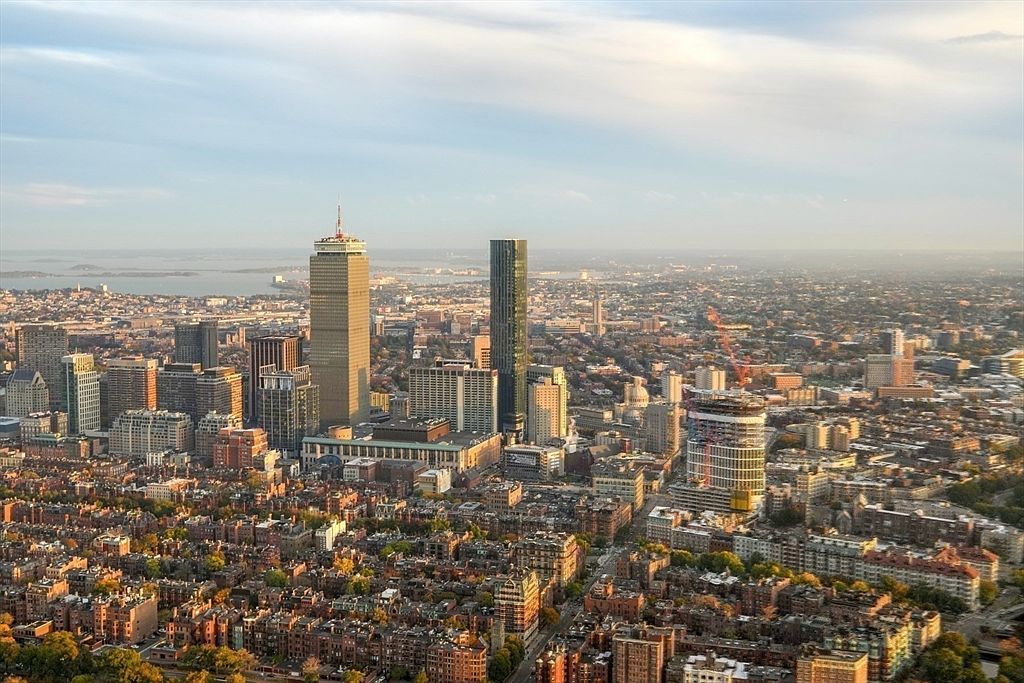 This aerial view showcases a sprawling cityscape with a mix of modern skyscrapers and traditional low-rise buildings. The image captures the urban density and architectural diversity of the city, highlighting key landmarks and the overall layout of residential and commercial areas. The perspective offers a comprehensive overview of the city's scale and urban planning.