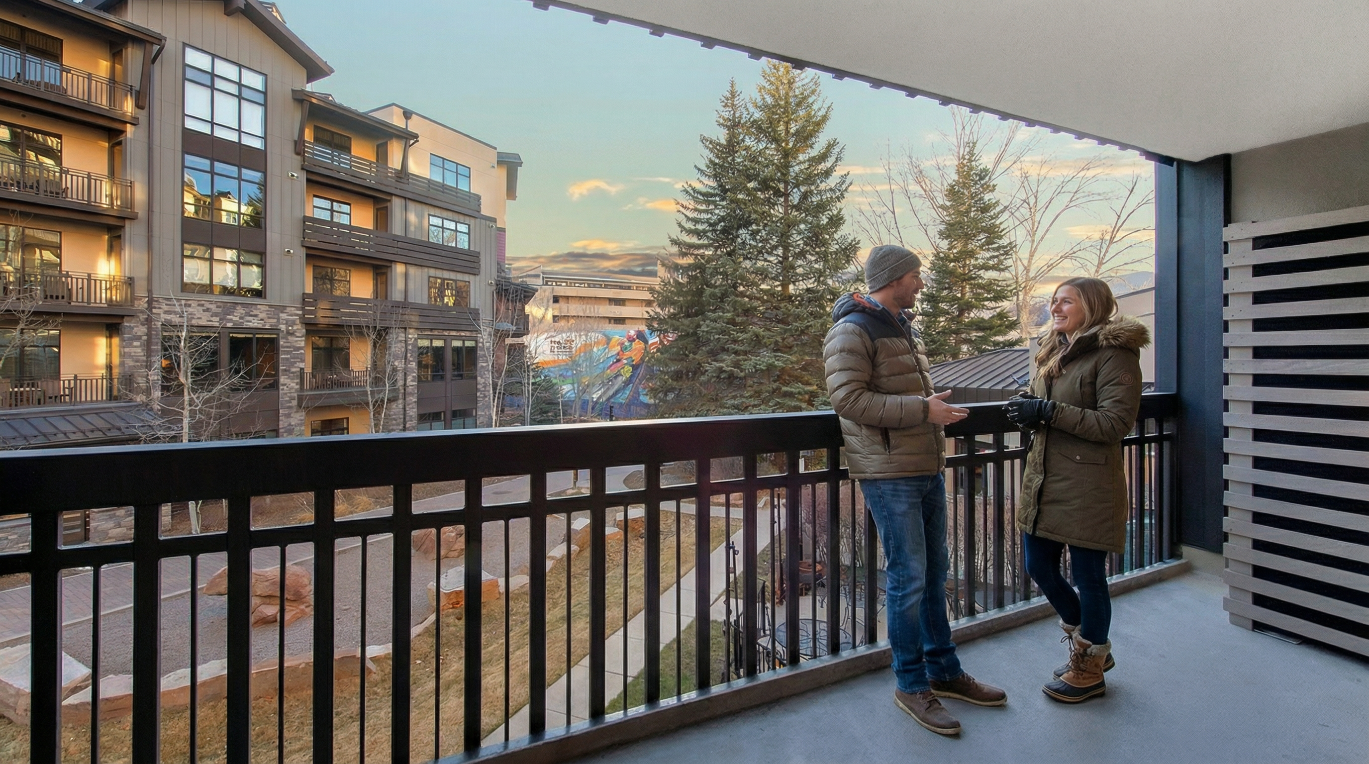 This outdoor deck offers a spacious spot for relaxation with a picturesque view of a modern multi-story residential building and nearby park areas. Featuring a durable black railing and comfortable access for residents, this space captures a serene, upscale lifestyle perfect for enjoying crisp mountain air. It provides an inviting and versatile area that enhances the overall appeal of the property.