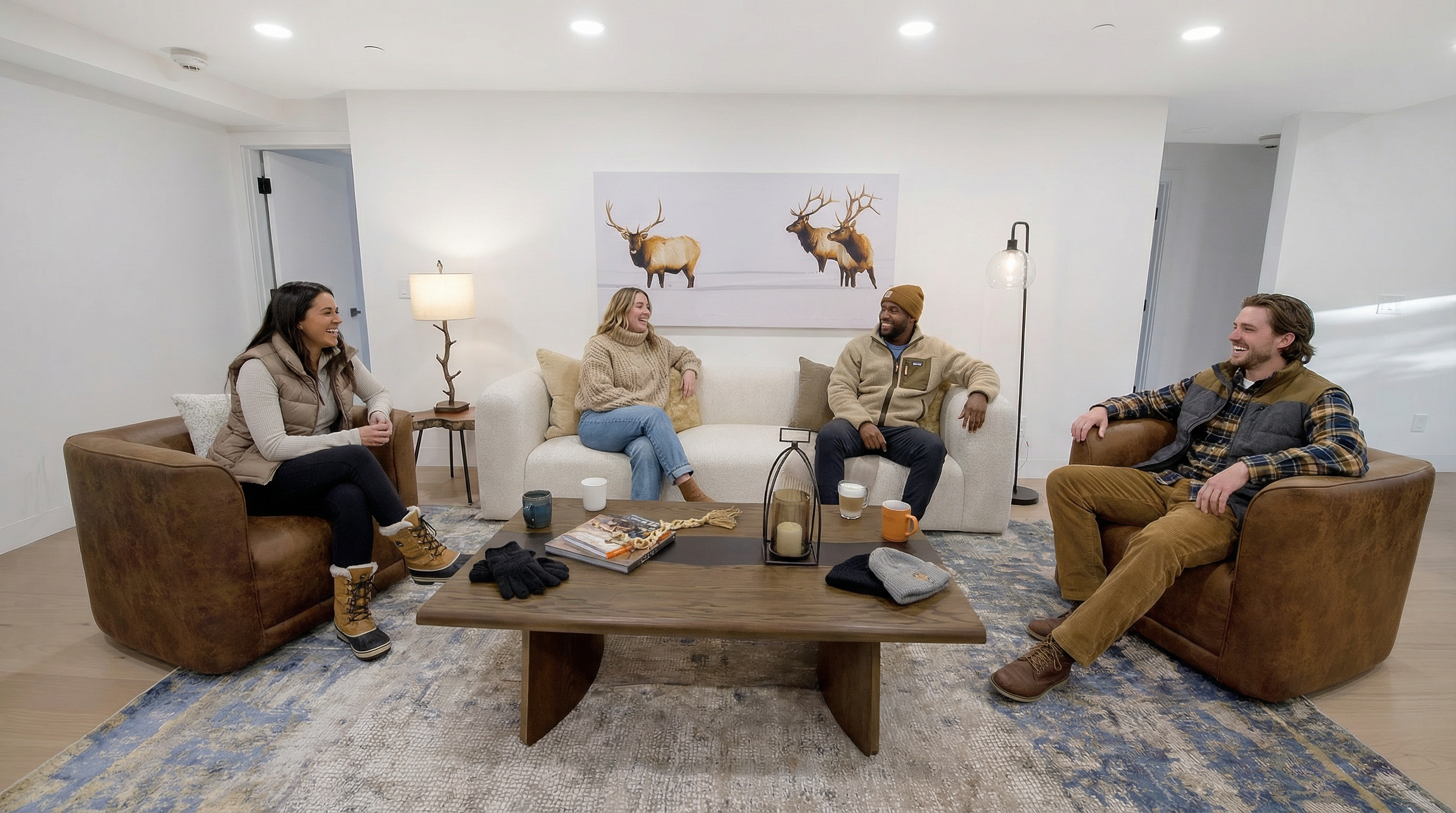 This inviting living room features a warm, rustic-modern aesthetic with a neutral color palette, plush cream-colored sofa, and rich brown leather armchairs. The space is anchored by a wooden coffee table and a large abstract print of elk on the wall, creating a cozy and comfortable atmosphere. It is a well-lit and stylishly staged room suitable for entertaining or relaxing, enhanced by a decorative area rug.