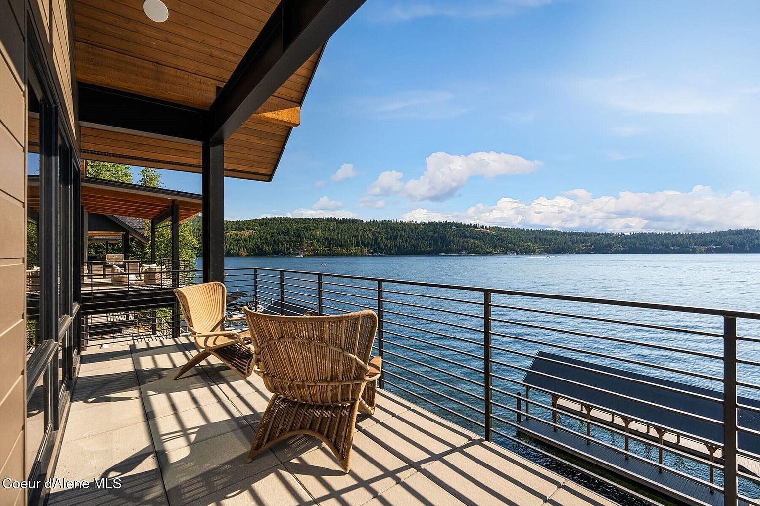 This image showcases a beautiful outdoor balcony with stunning waterfront views. The balcony features modern railings, comfortable wicker chairs, and a sleek, contemporary design. The scene evokes a sense of luxury and relaxation, highlighting the property's prime location and outdoor living space.