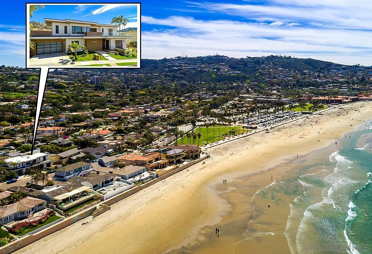 This aerial view showcases a stunning coastal property with a modern architectural design. The home is situated near a sandy beach, with a clear view of the ocean and surrounding neighborhood. The image highlights the property's prime location and luxurious appeal, emphasizing its proximity to both residential areas and recreational amenities.