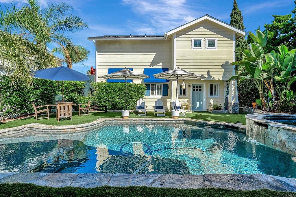 This image showcases a beautiful backyard featuring a swimming pool and spa. The pool is surrounded by well-maintained landscaping and patio furniture, creating an inviting outdoor living space. The house, with its charming architectural details, serves as a backdrop to this serene setting, enhancing the property's appeal.