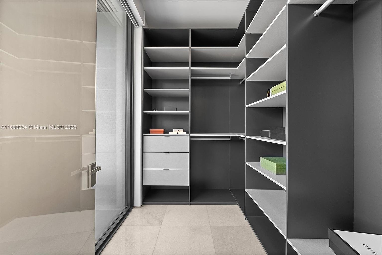 This is a well-organized walk-in closet featuring a combination of open shelving, drawers, and hanging rods. The color scheme is a modern gray and white, creating a clean and sophisticated look. The closet appears spacious and designed for efficient storage.