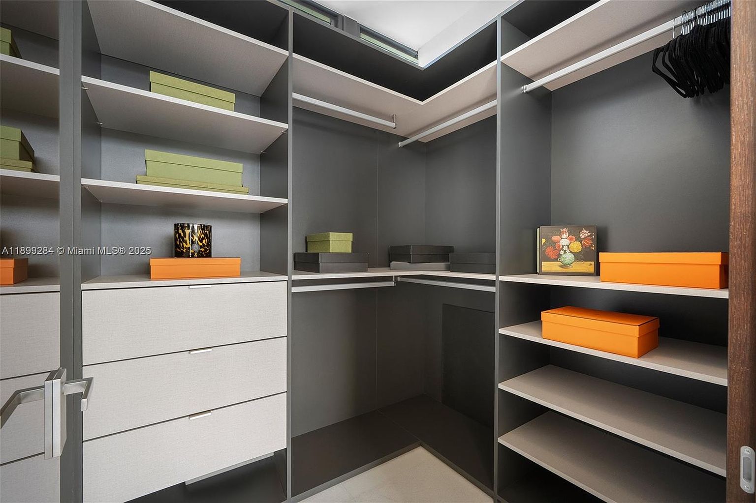This is a well-organized walk-in closet featuring a gray and white color scheme. The closet includes shelving, drawers, and hanging space, providing ample storage. The design is modern and functional, ideal for showcasing the storage capacity of the property.