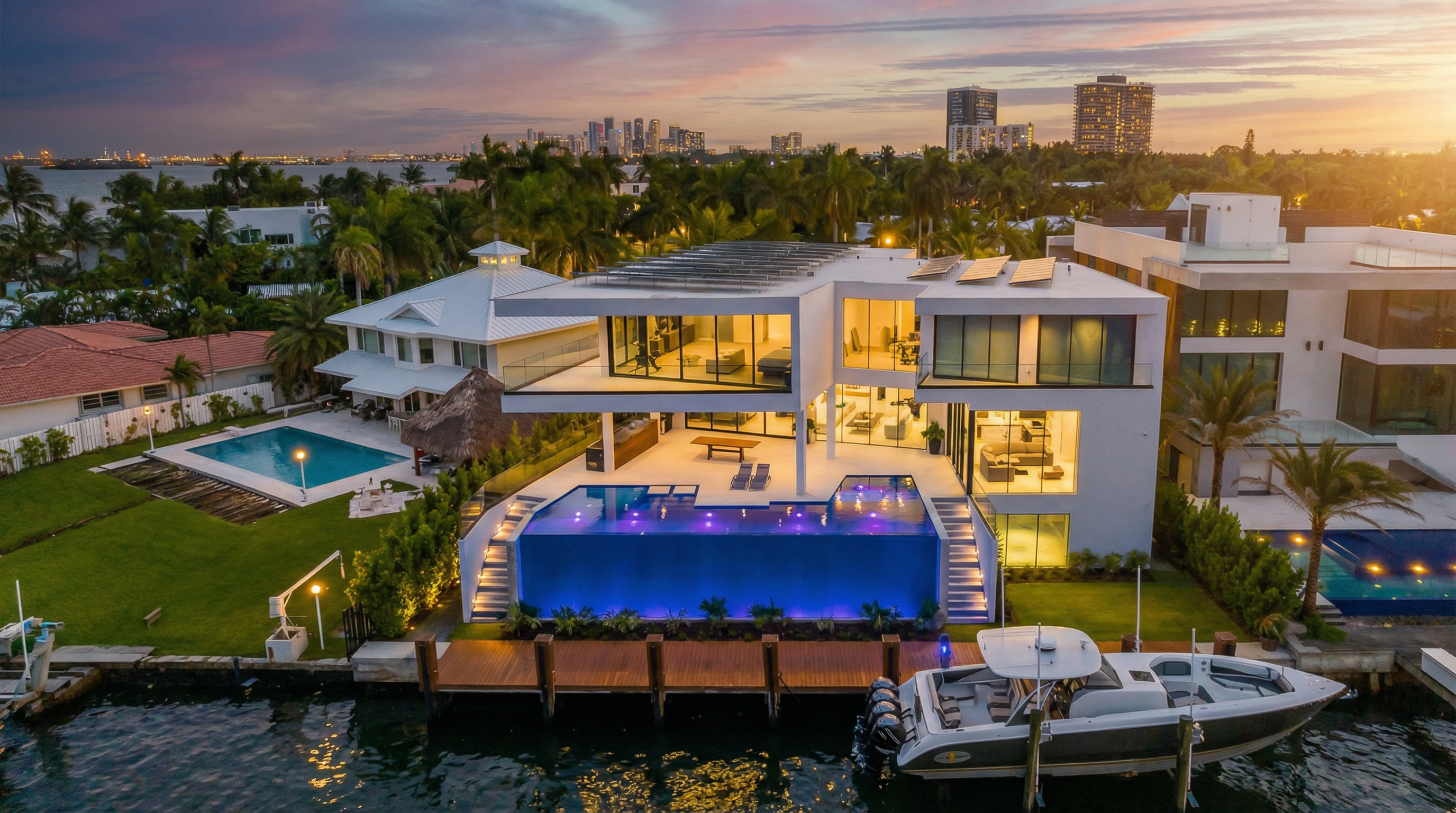 This stunning contemporary waterfront estate features a striking infinity-edge pool, multi-level terraces, and expansive floor-to-ceiling glass walls. The property includes a private deep-water dock with a large boat, lush tropical landscaping, and solar panels, all set against a beautiful sunset backdrop. It offers a sophisticated, modern aesthetic that perfectly captures the luxury lifestyle in a prime coastal location.
