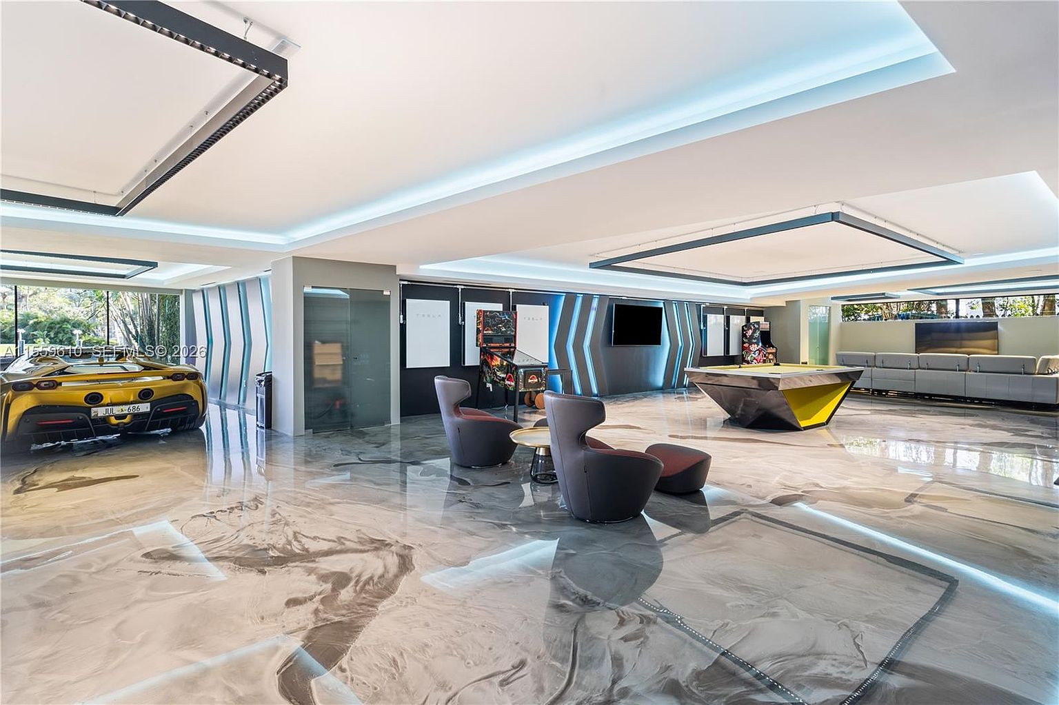 This is a modern and luxurious living room featuring a unique epoxy floor with a marble-like design. The room includes a yellow sports car, a pool table, a seating area with modern chairs, and a large gray sofa. The lighting is contemporary, with recessed lights and accent lighting that highlights the architectural details.