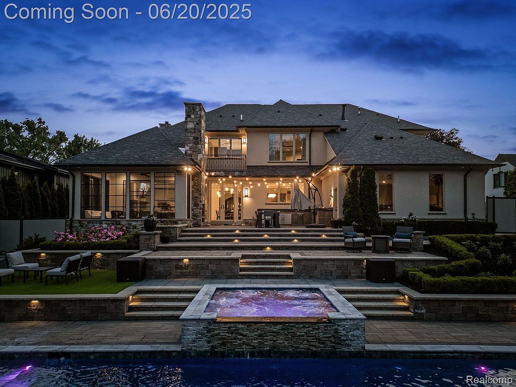 This image showcases the luxurious backyard of a property, featuring a stunning pool and spa area. The multi-tiered patio includes outdoor seating and lighting, creating an inviting space for relaxation and entertainment. The well-maintained landscaping adds to the overall appeal of this outdoor oasis.