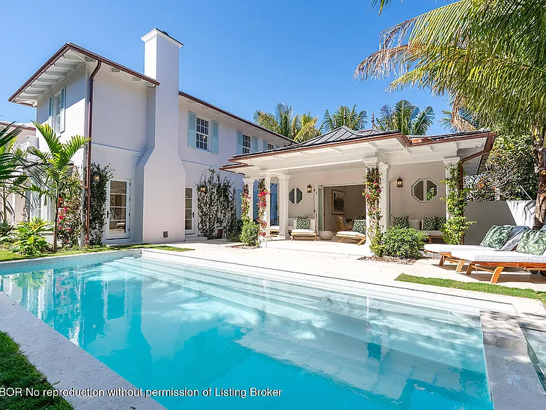 This image showcases a beautiful backyard pool area, ideal for relaxation and entertainment. The pool's clear turquoise water is inviting, while the surrounding patio features stylish lounge furniture and lush landscaping. The well-maintained exterior of the home complements the sophisticated ambiance of the outdoor space.