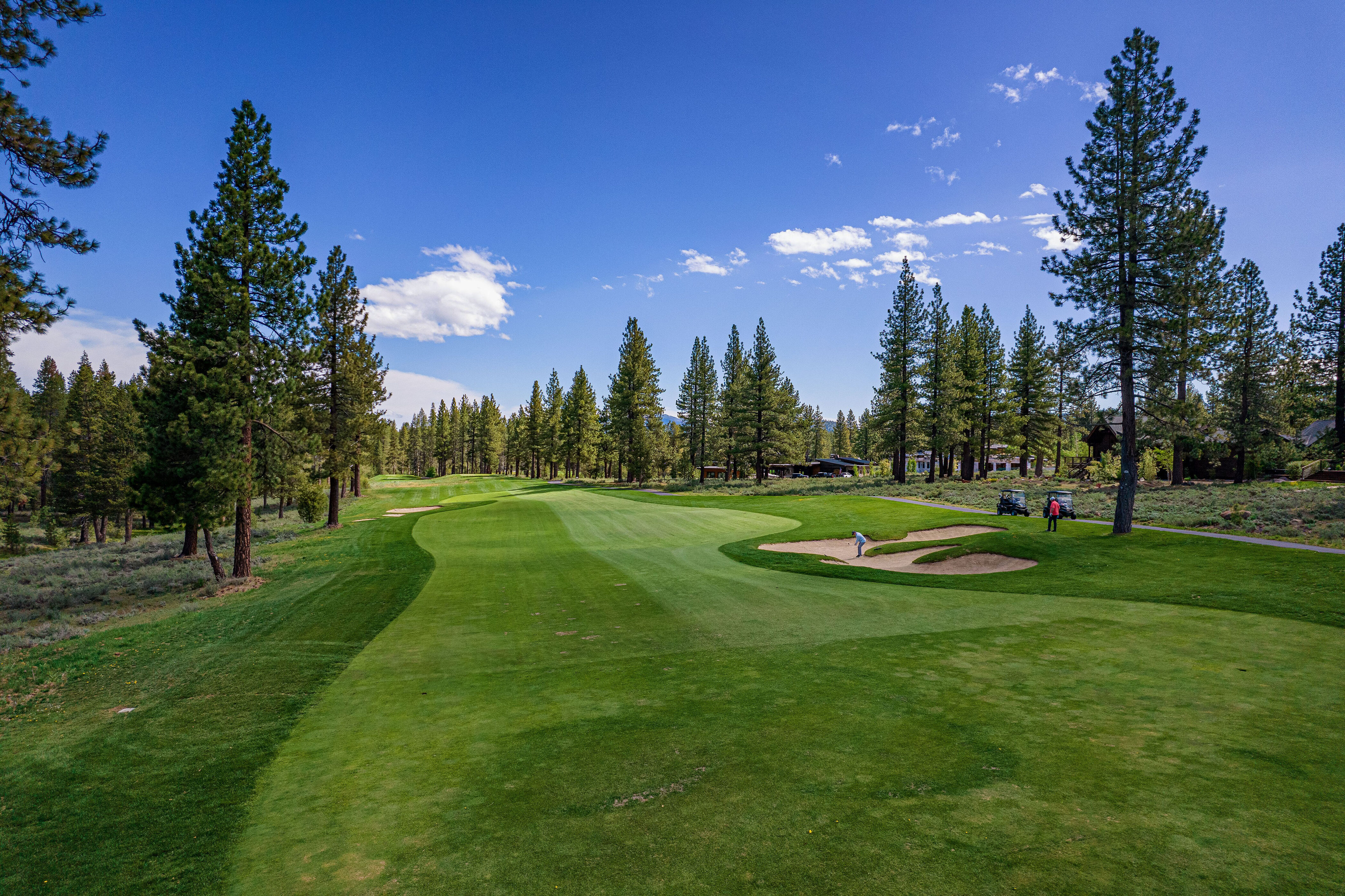 This aerial shot showcases a well-maintained golf course on a clear day. The image highlights the lush green fairway, sand traps, and strategically placed trees. The scene conveys a sense of exclusivity and recreational opportunity, ideal for attracting golf enthusiasts.