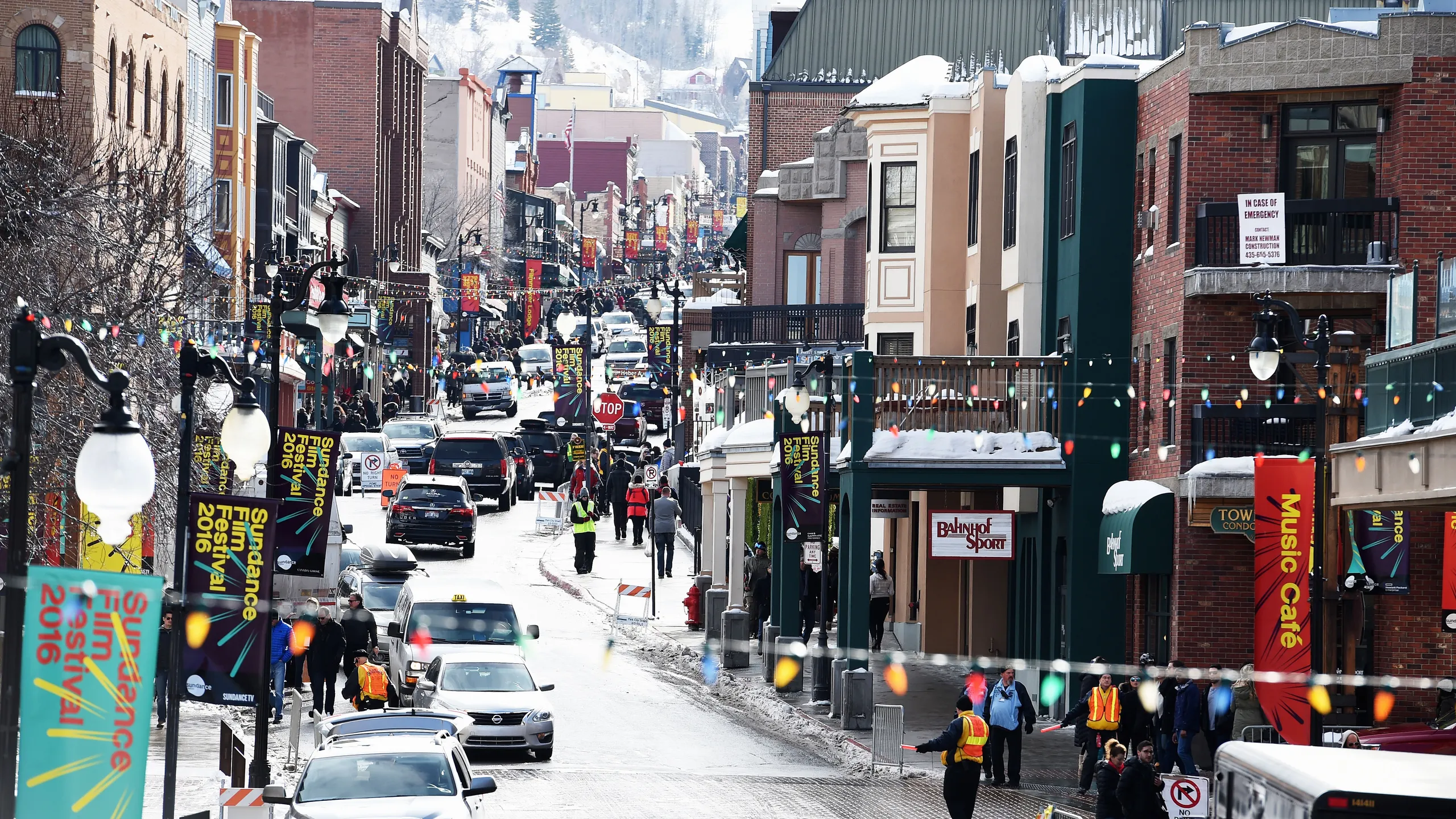 This image presents a bustling street scene, likely a downtown area, bustling with activity. It is decorated with seasonal banners and festive lighting, implying a holiday season or special event. Several commercial buildings line the street, offering various retail and dining options, creating a dynamic and engaging atmosphere for potential residents or businesses.