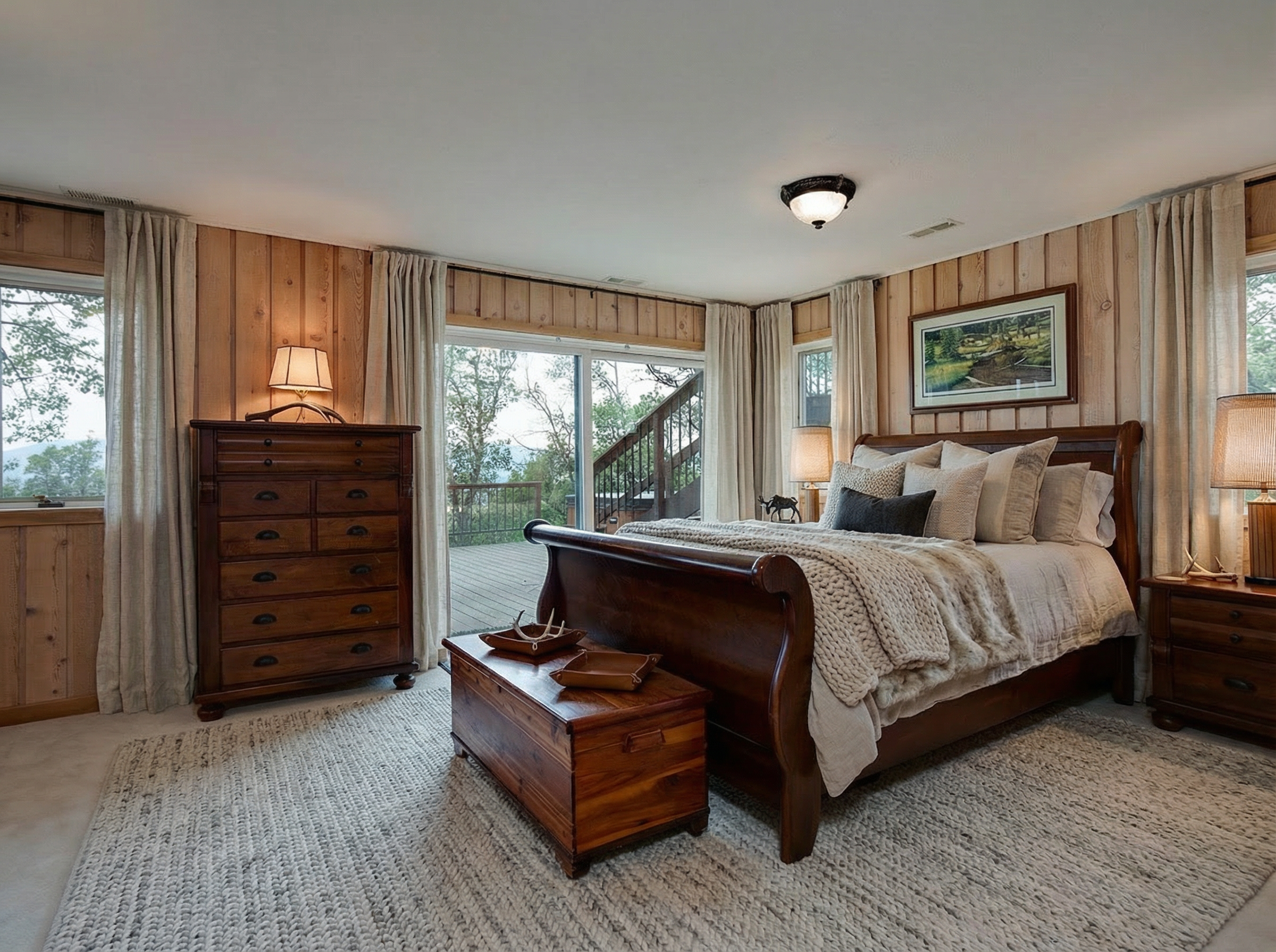 This is a cozy primary bedroom featuring wood-paneled walls and a neutral color palette. A large wooden bed is the focal point, adorned with layers of blankets and pillows. The room also includes a dresser, a chest, and nightstands, all in a matching wood finish contributing to a warm and inviting atmosphere.