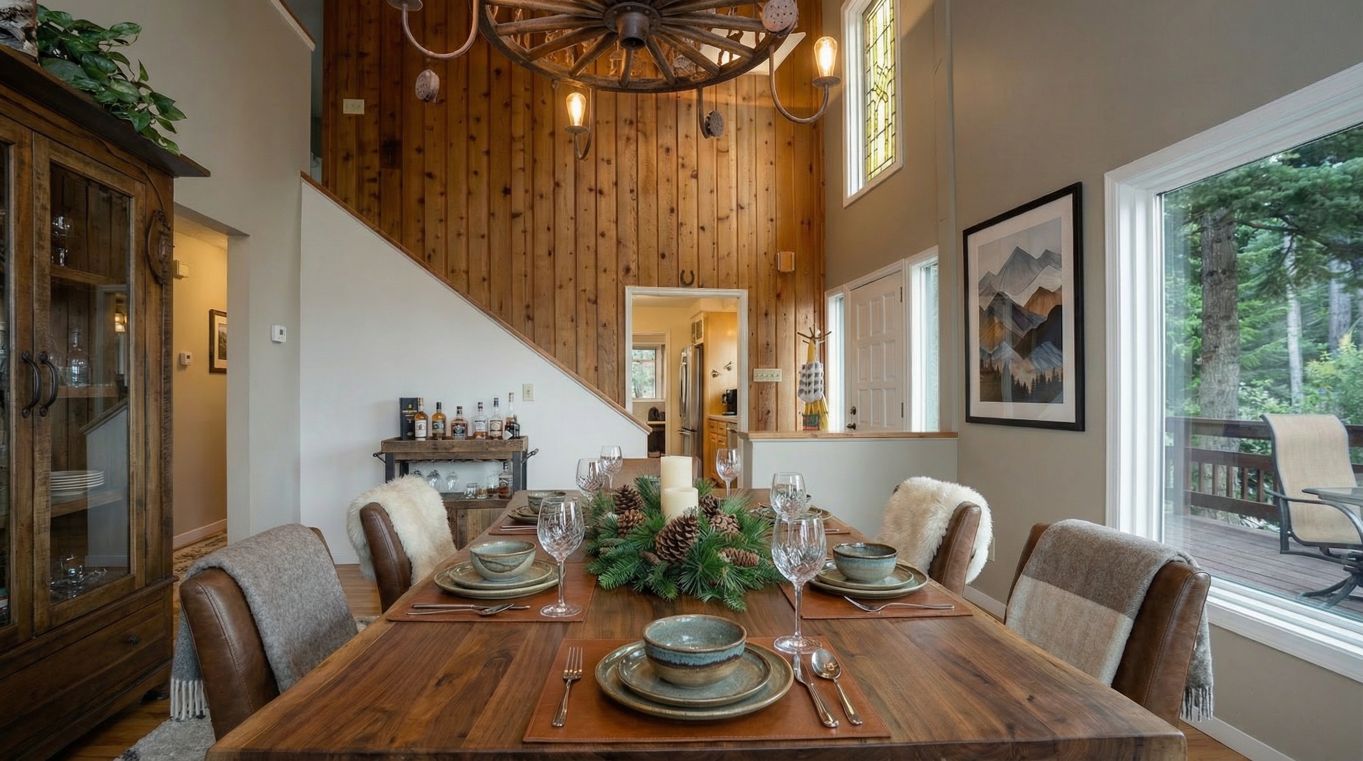 This inviting dining room features a large wooden table set for a meal, complemented by leather chairs and decorative details like a pinecone centerpiece. The room is well-lit, with a warm ambiance created by the lighting fixtures and natural light from a nearby window. Adjacent to the dining area is a wooden cabinet, adding extra storage and character to the space.