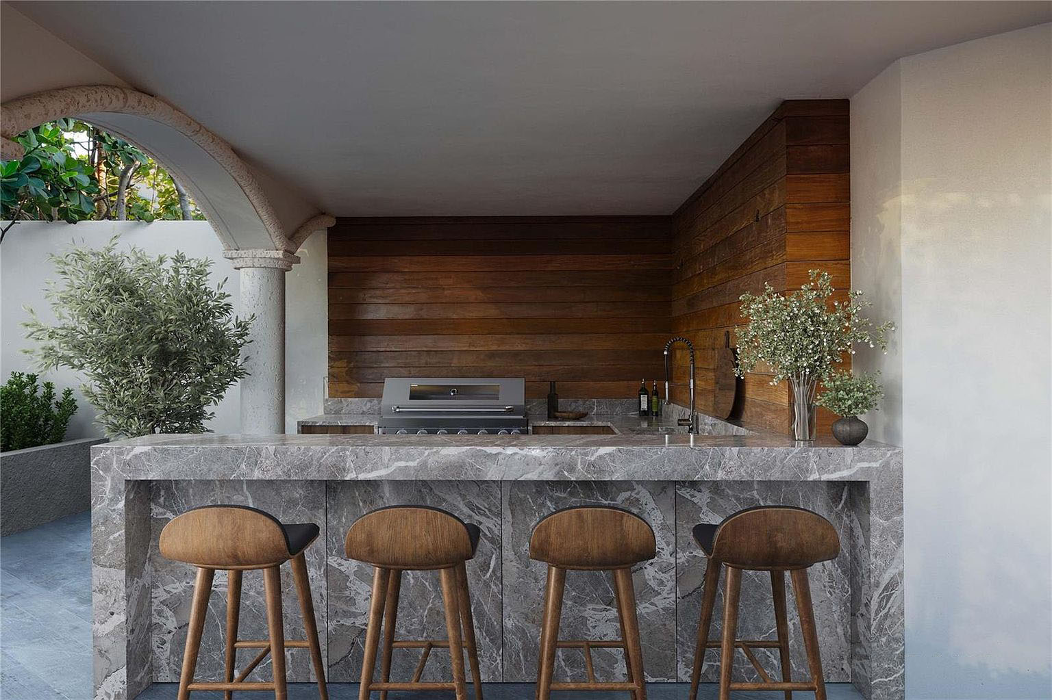 This image showcases an outdoor kitchen and bar area. The countertop is made of marble, and there are four bar stools. The outdoor space also features a built-in grill and sink, perfect for entertaining.