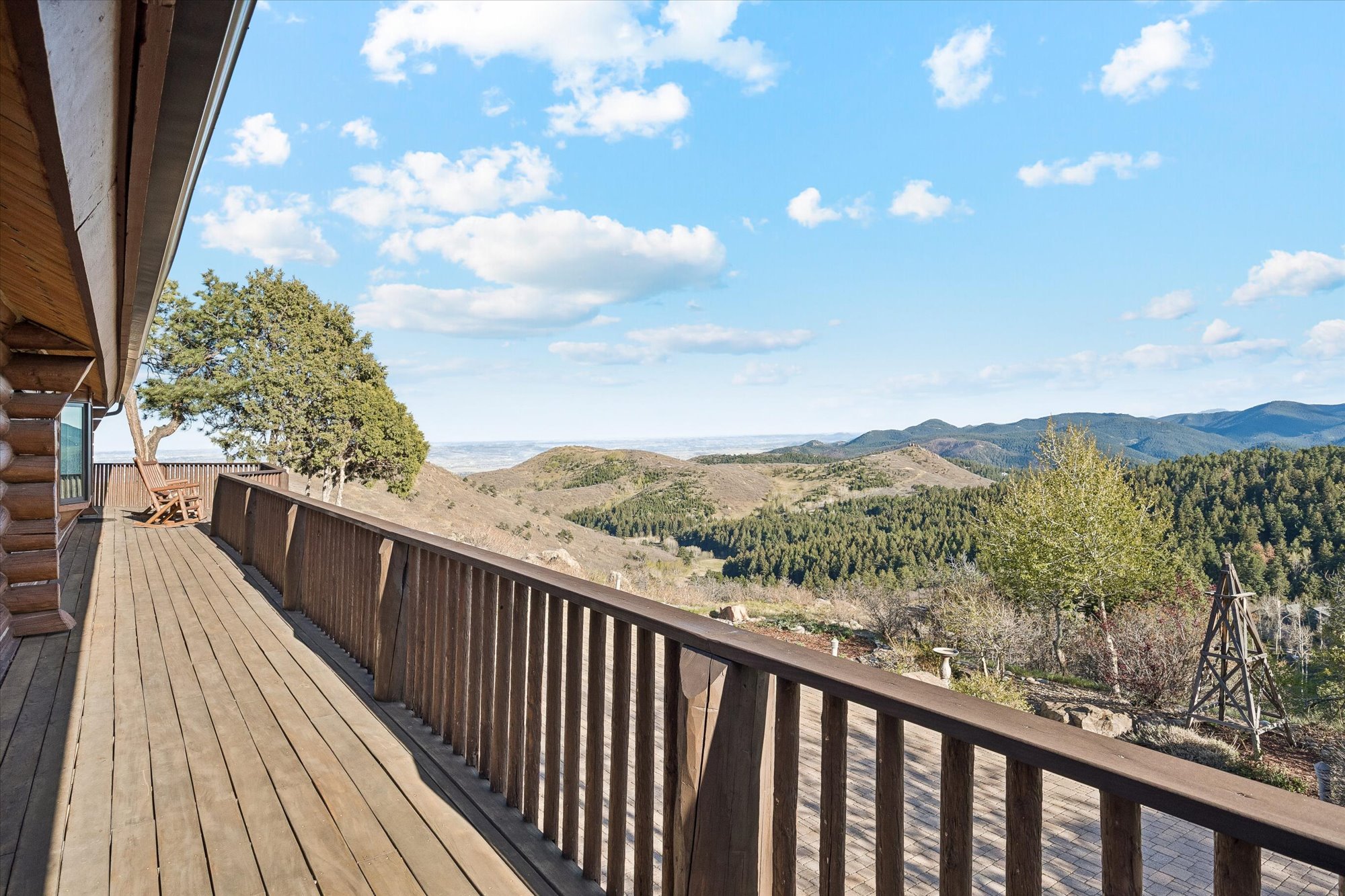 This spacious wooden deck features a warm, rustic log construction and expansive views of the rolling mountain landscape. Complete with a wooden chair for seating, the deck offers a scenic and peaceful vantage point, ideal for outdoor relaxation. Its elevated position highlights the property's natural surroundings and connection to the mountainous terrain.