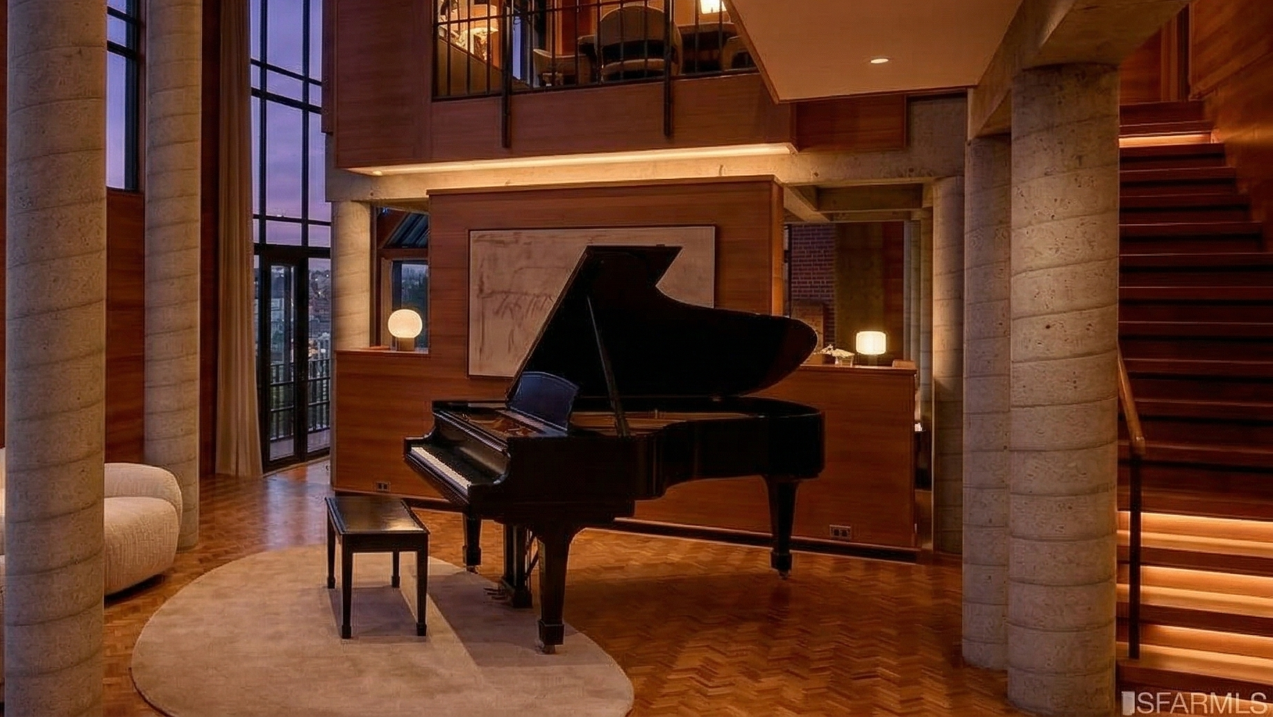 This sophisticated, double-height living room features a striking grand piano as its focal point, set atop a plush oval rug. The space is anchored by textural concrete pillars and warm wood paneling, complemented by a dramatic floating staircase with integrated illumination. Large, multi-story windows invite natural light and provide an elegant, open-concept feel perfect for high-end residential living.