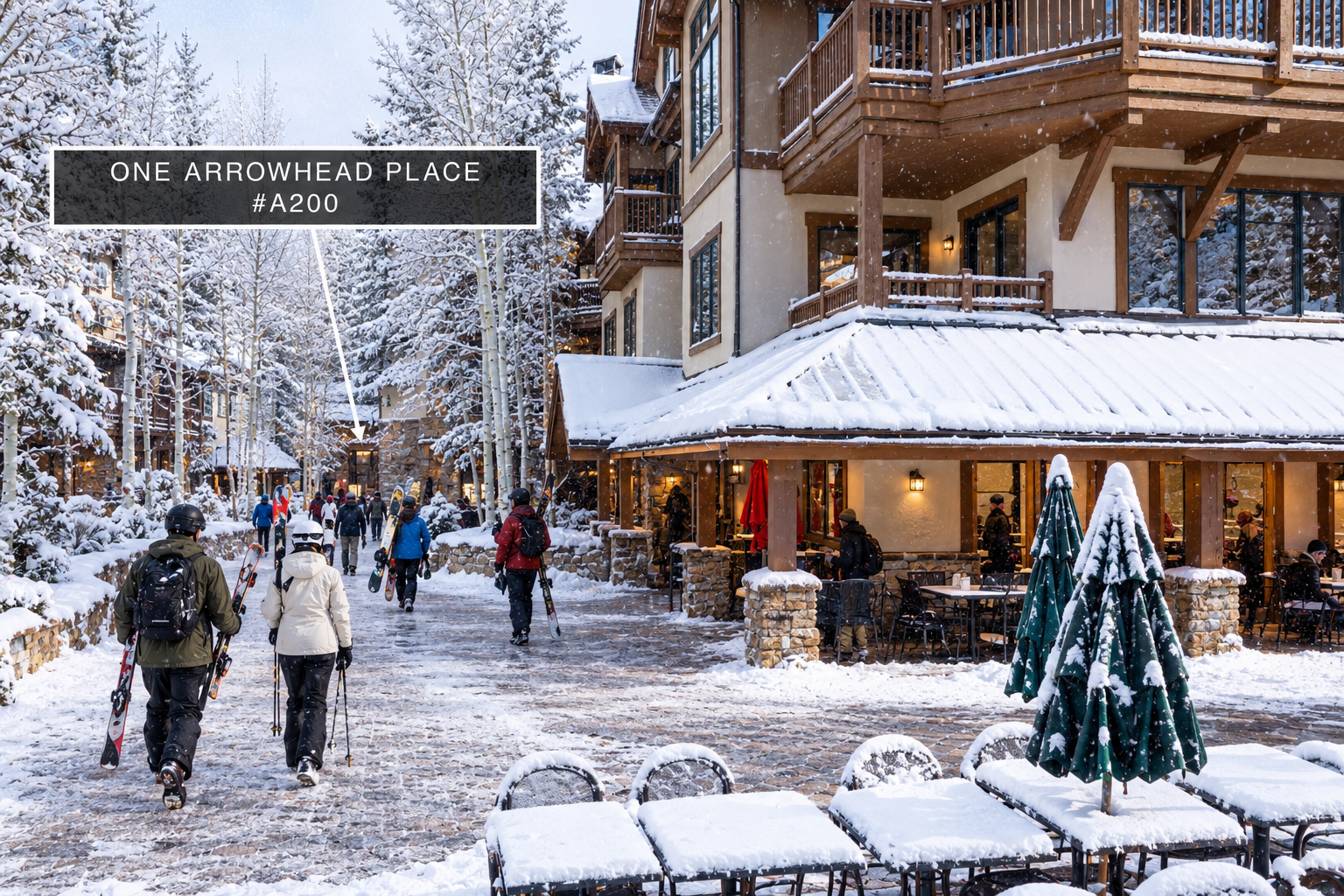 This image showcases a snowy, picturesque courtyard leading to the entrance of 'One Arrowhead Place', characterized by alpine-style architecture with wood and stone detailing. The scene features pedestrians carrying ski equipment, highlighting the property's convenient location in a resort area. The presence of outdoor seating covered in snow suggests an inviting, lively atmosphere suitable for mountain living.
