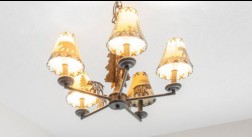 This image features a rustic-style chandelier designed with nature-themed accents. The light fixture is adorned with silhouettes of animals and trees on its shades and center post, perfect for a lodge or farmhouse interior aesthetic. It provides a warm, inviting lighting element suitable for a dining area or great room.