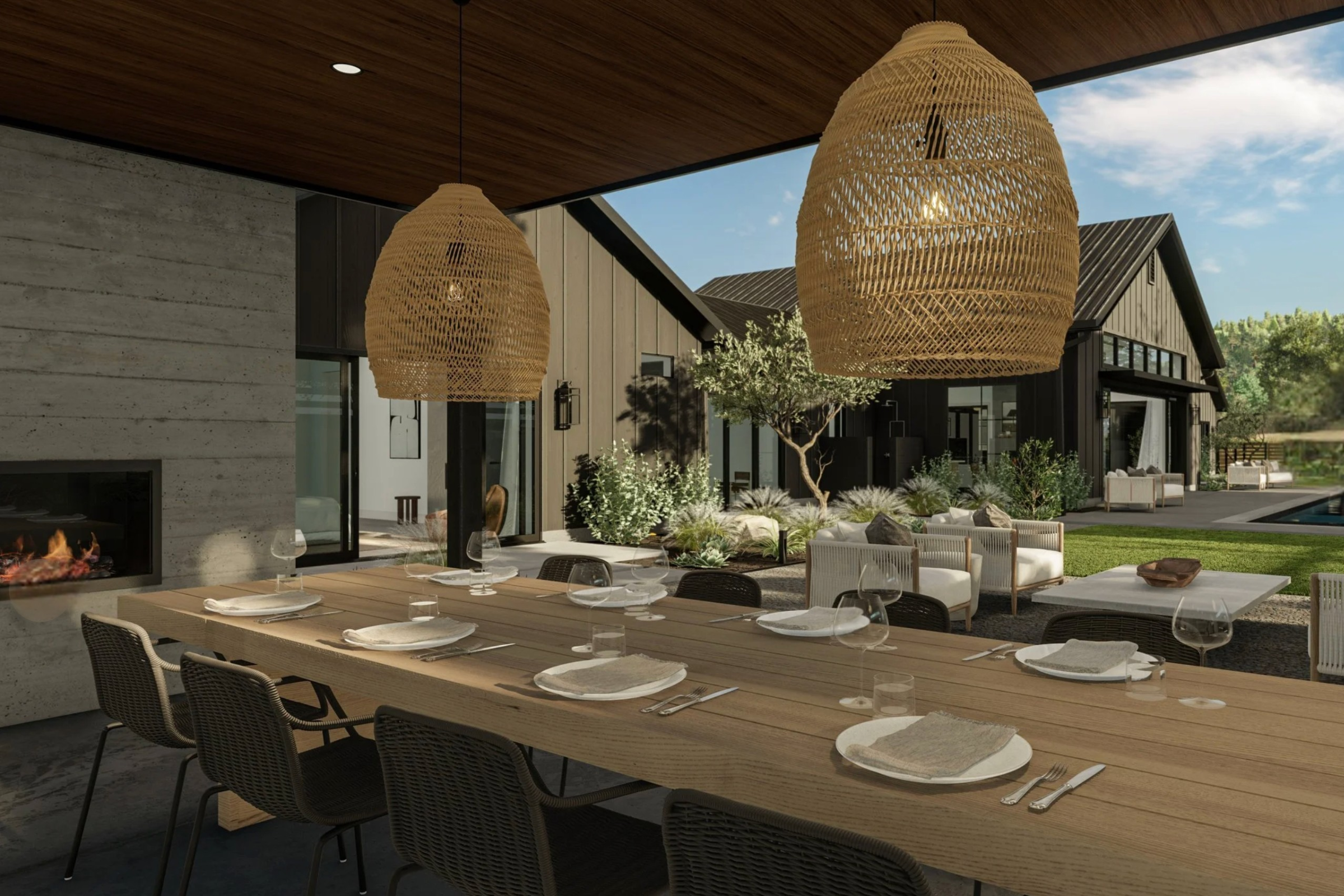 This sophisticated outdoor dining area features a long, natural wood table set for a formal meal under a covered patio, complete with a modern built-in fireplace. The space is accented by large, woven pendant lights and overlooks a beautifully landscaped courtyard with contemporary outdoor lounge furniture. The overall aesthetic is a seamless blend of luxury, modern farmhouse architecture, and serene indoor-outdoor living.