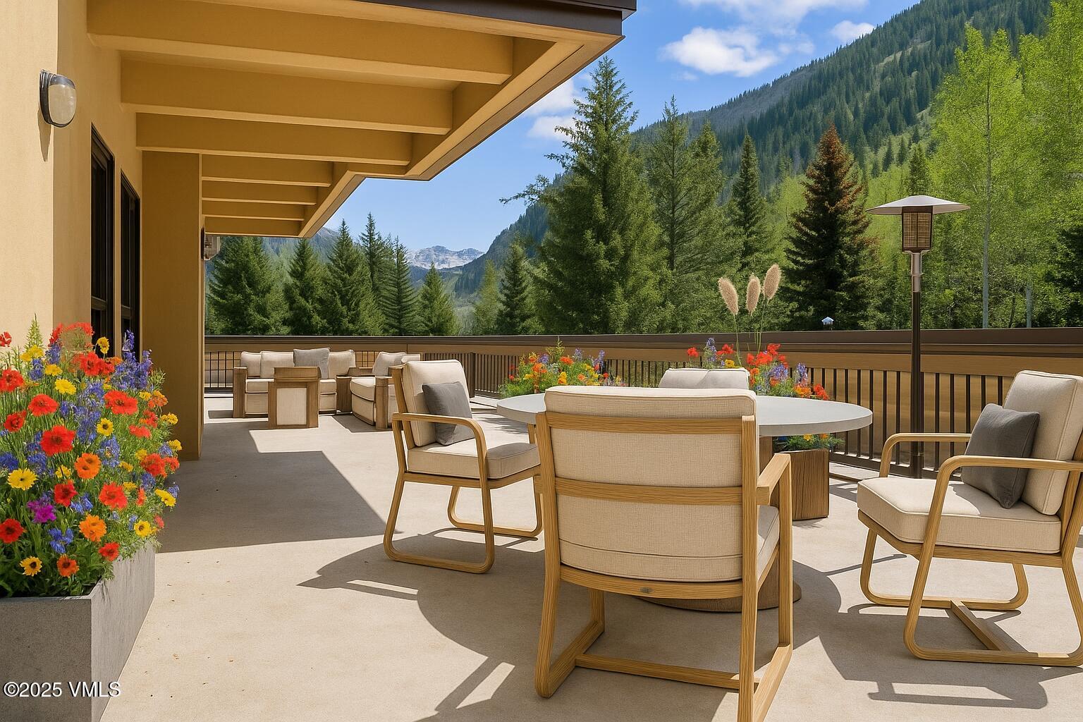 This spacious, covered outdoor deck features modern patio furniture, including a dining set with cushioned chairs and lounge seating. Large planters overflowing with vibrant, multicolored wildflowers provide color, while the deck overlooks a breathtaking mountain landscape and dense forest. The setting is luxurious and serene, perfect for outdoor relaxation or entertaining in a scenic mountain environment.