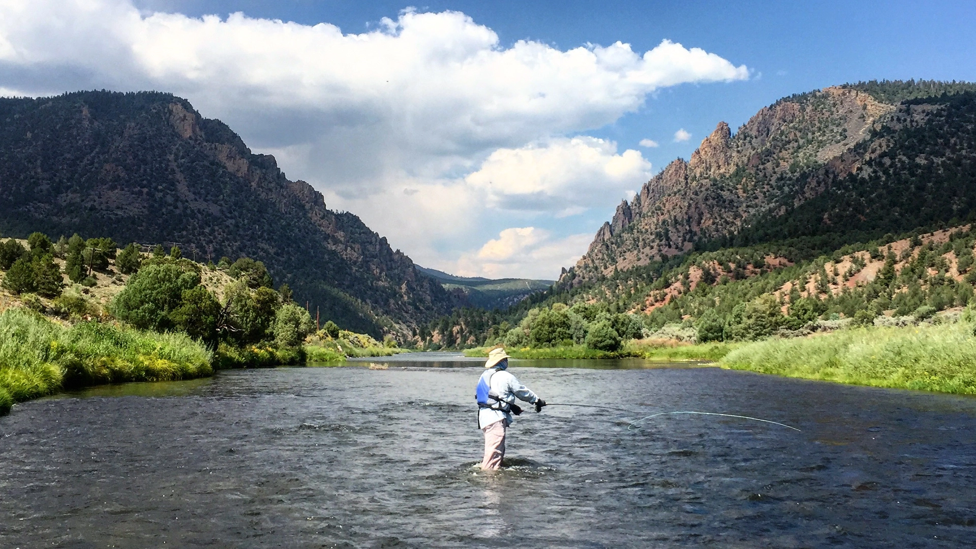 This image highlights a scenic riverfront setting, showcasing the natural beauty and outdoor recreational opportunities available to the community. A fly fisherman is captured in the center, emphasizing the peaceful and pristine environment of the river nestled between mountain ridges. This area serves as a desirable lifestyle amenity, perfect for those seeking proximity to nature and outdoor activities.